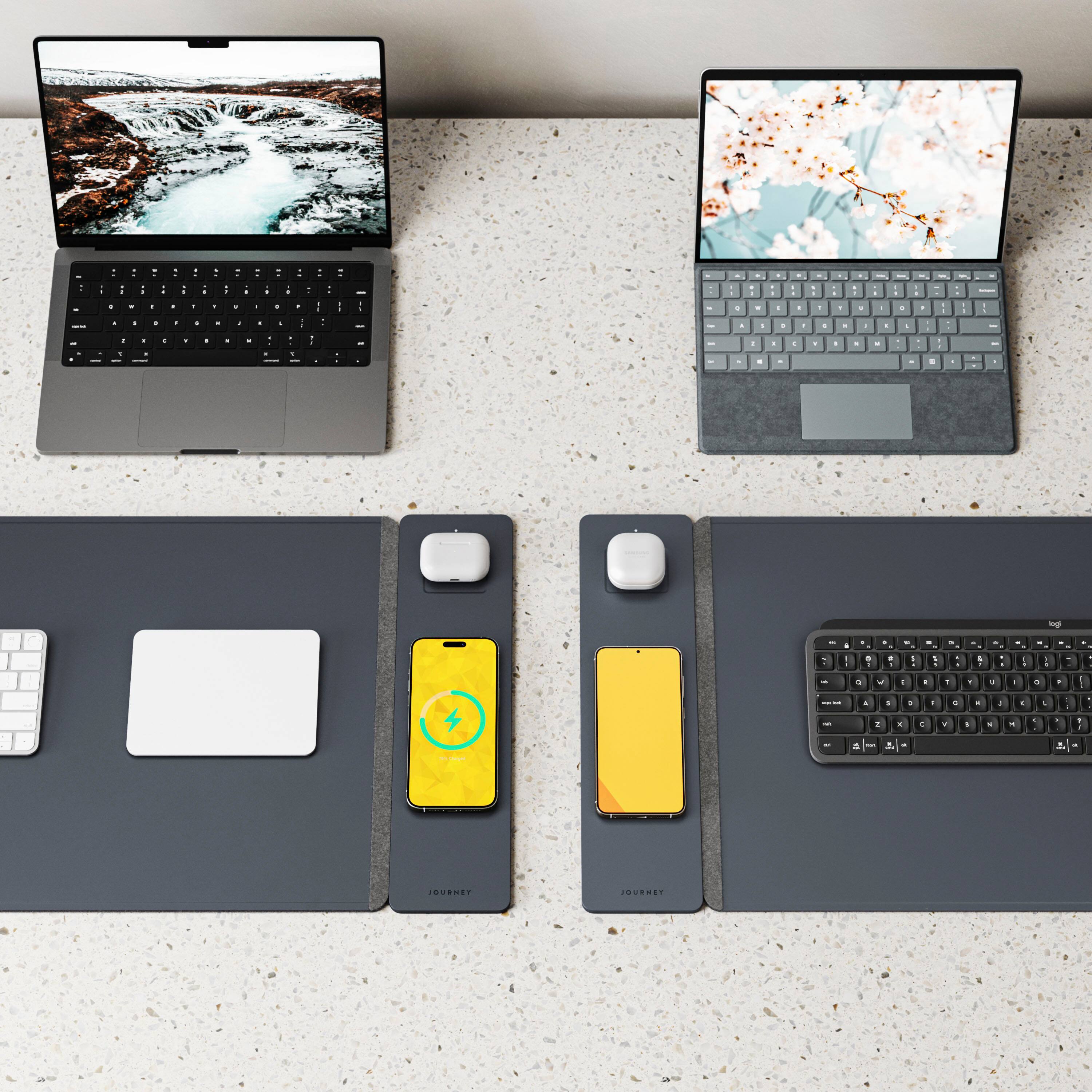 The image features two laptops placed on a table, with a mouse and a keyboard in between them. The laptops are positioned side by side, and the mouse and keyboard are placed in front of them. The table appears to be a granite countertop, providing a sturdy and elegant surface for the laptops and accessories. This setup suggests that the laptops are being used for work or personal purposes, with the mouse and keyboard providing additional input devices for easier navigation and typing.