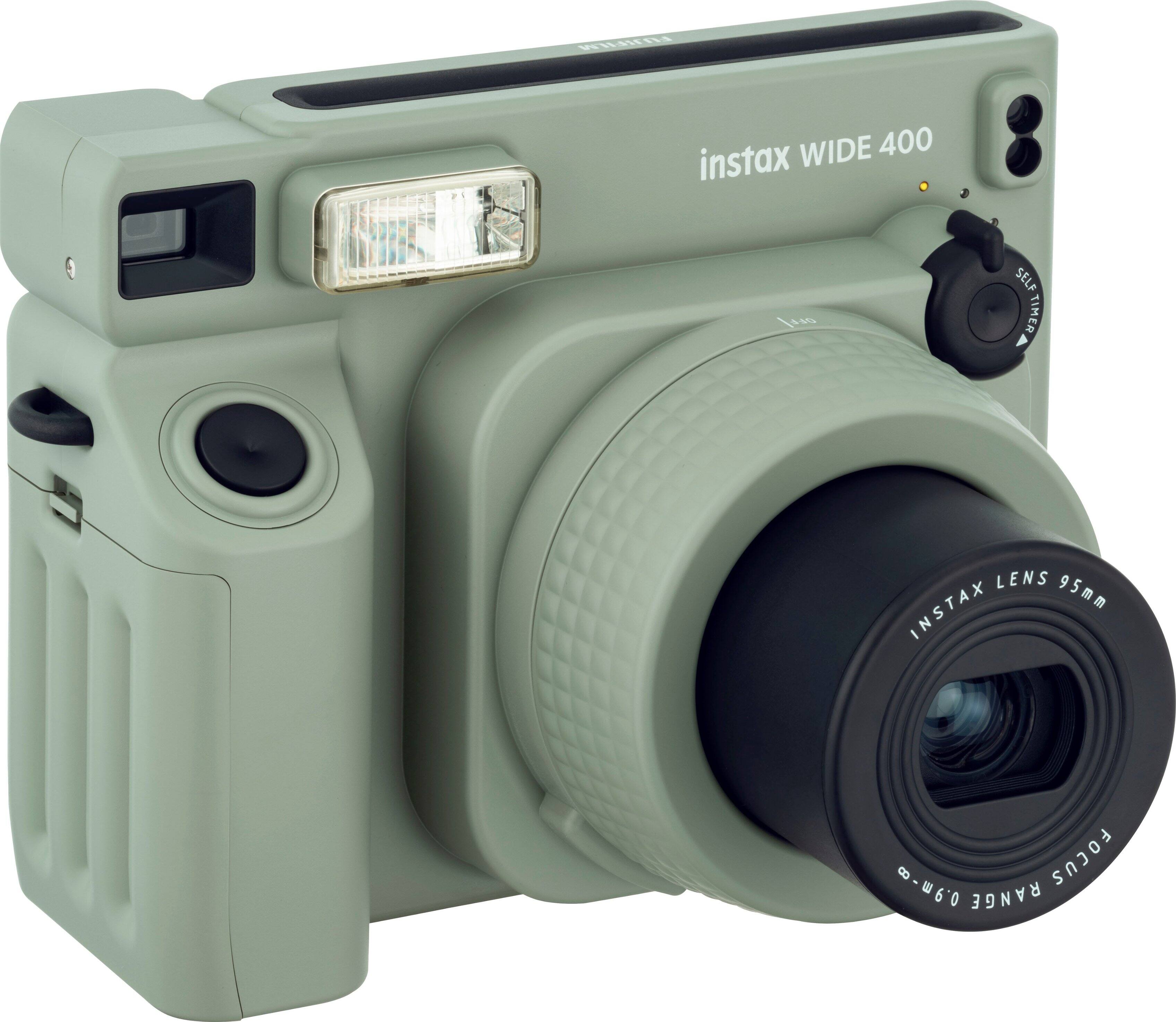 The image features a green Instax Wide 400 camera with a lens. The camera has a self-timer lens and a focus range of 95mm - 60.