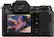 The image features a black digital camera with a large viewing screen. The camera has a viewfinder and a menu, which includes options for drive mode, autofocus, and display settings. The camera is designed for capturing high-quality images and is likely used by photographers for professional or personal use.