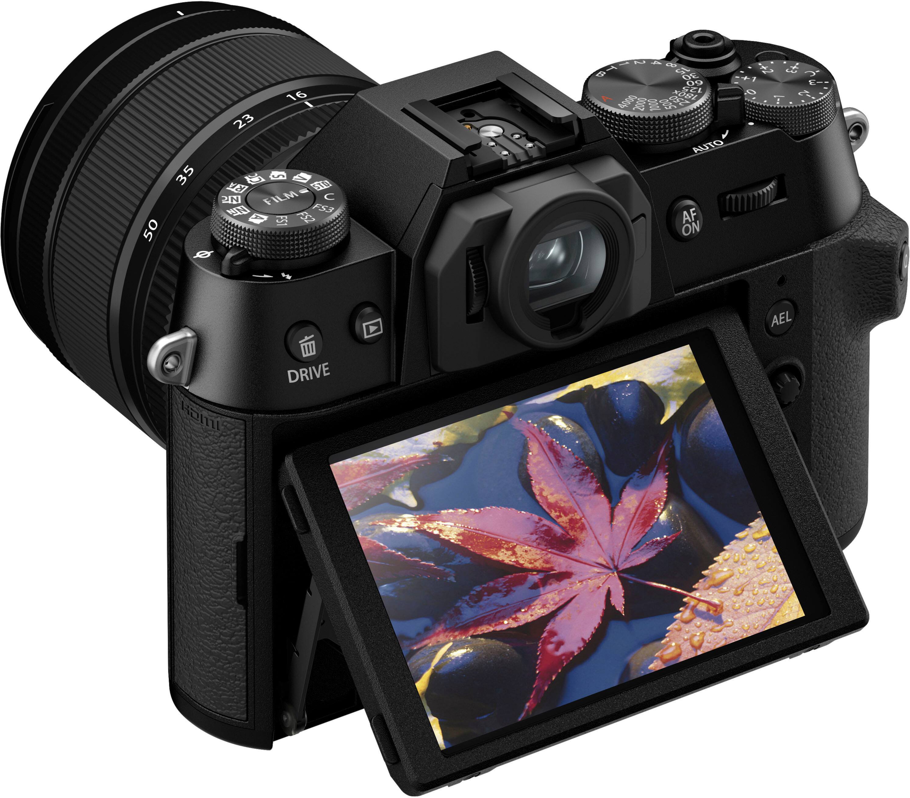 The image features a digital camera with a large screen and a viewfinder. The camera has a black color scheme and is equipped with a lens and a flash. The camera is turned on, and the screen displays the time as 10:51. The viewfinder is open, and the camera is ready for use. The camera is positioned on a flat surface, possibly a table, and is the main focus of the image.