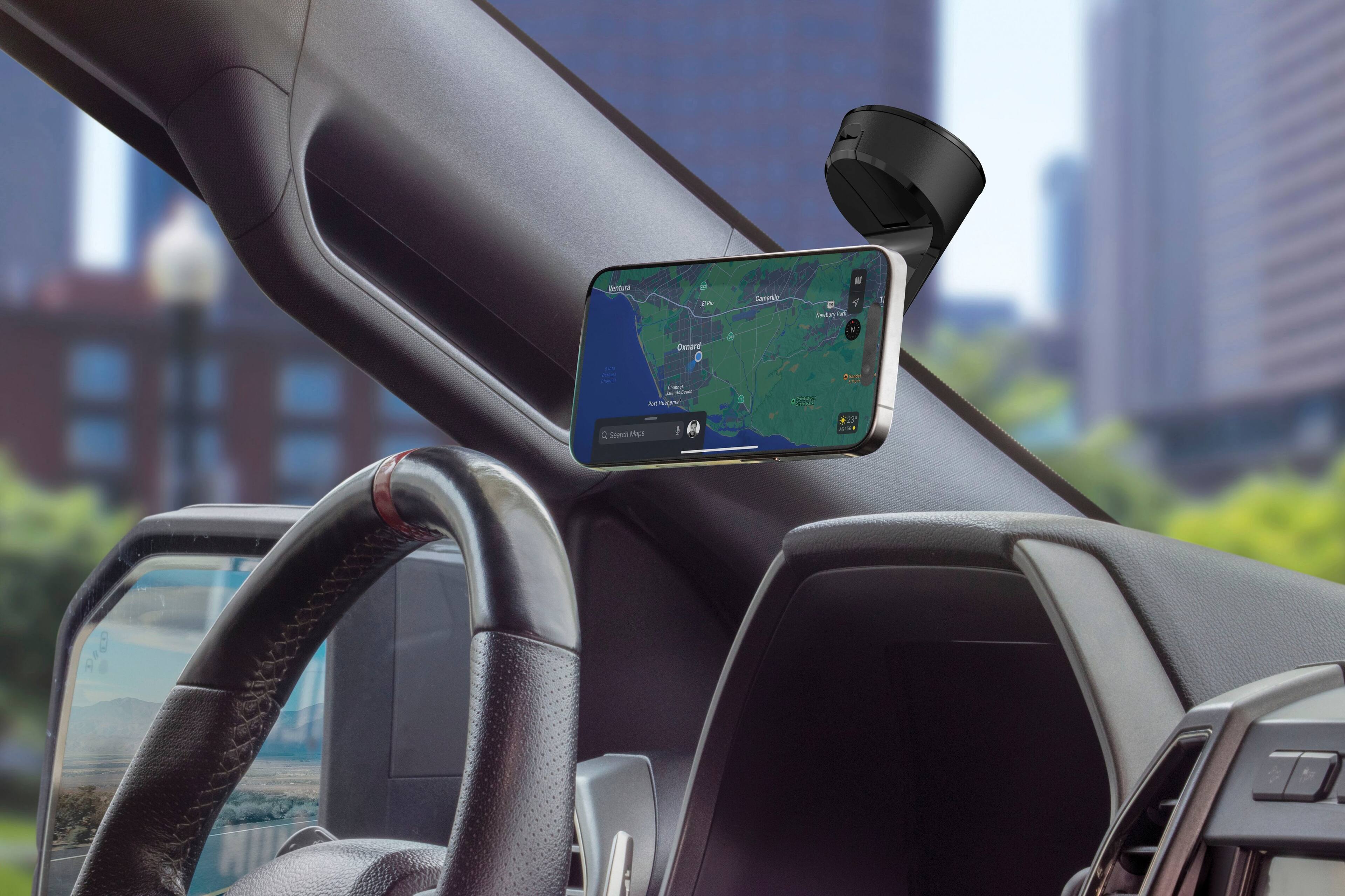 The image shows a car's dashboard with a GPS device mounted on it. The GPS is displaying a map of the area, showing the location of the car in relation to the surrounding streets. The car is parked in a parking lot, and the GPS is providing directions to the driver. The image also features a steering wheel and a view of the city in the background.