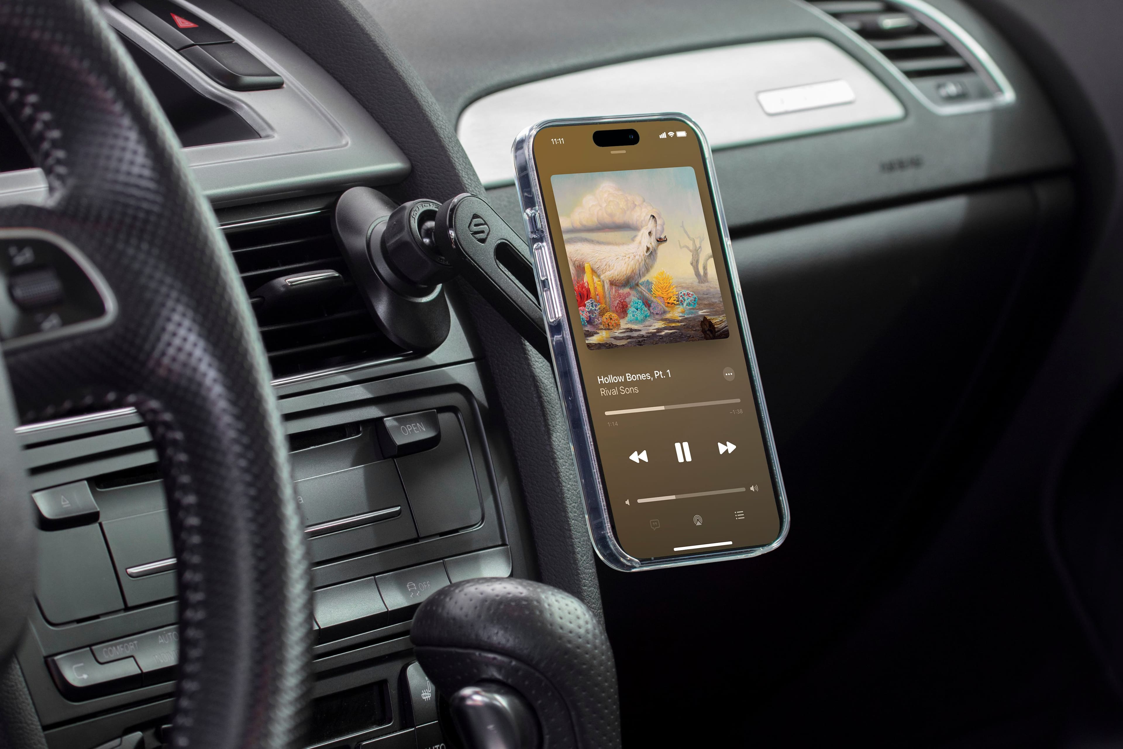 The image shows a car interior with a cell phone placed on the dashboard. The cell phone is connected to the car's speaker system, allowing the driver to listen to music or other audio content. The phone is displaying the album cover of "Bones" by Hollow Rival Sons. The time displayed on the phone is 11:71.