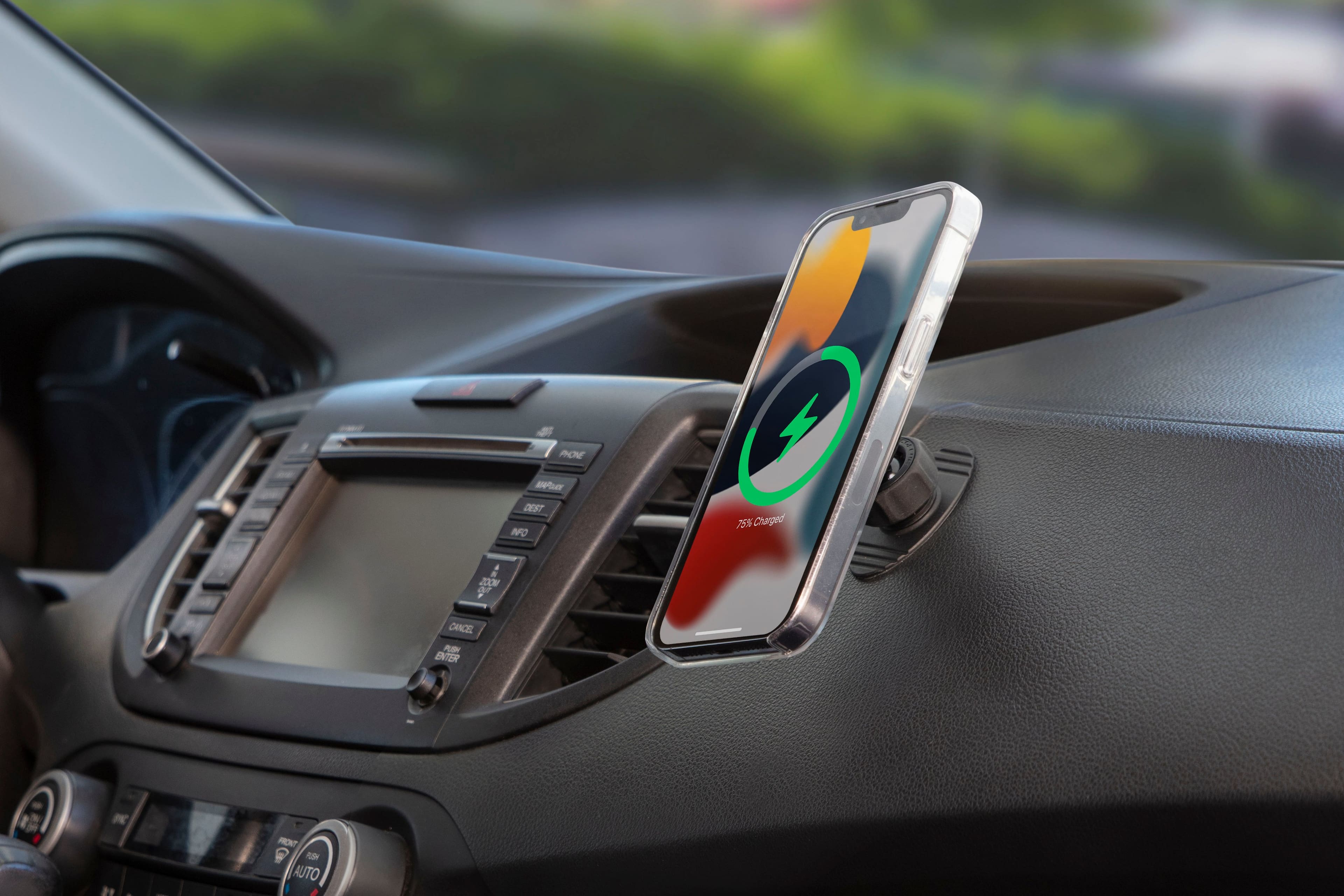 The image shows a cell phone mounted on a car's dashboard, displaying a battery level of 75%. The phone is positioned in the center of the dashboard, and the car appears to be parked.