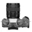 The image features a close-up of a camera with a zoom lens, which is a digital camera. The camera has a black lens and a silver body. The lens is a 16-50mm zoom lens, which is suitable for capturing various types of shots, from wide-angle to telephoto. The camera also has a zoom control, allowing the user to adjust the focal length of the lens. The camera is designed to capture high-quality images and is suitable for both professional and amateur photographers.