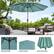 The image features a large blue umbrella with a canopy, providing shade and protection from the sun. The umbrella is situated next to a patio table with chairs, creating a comfortable outdoor seating area. The umbrella is open and ready for use, offering a relaxing spot to enjoy the outdoors.