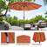 The image features an orange umbrella with a push button tilt function, which allows it to be easily adjusted for optimal shade. The umbrella is weather-resistant and has an anti-fade vented canopy, ensuring that it remains durable and provides shade effectively in various weather conditions. The umbrella is set up on a patio table, surrounded by chairs, creating a comfortable outdoor seating area.