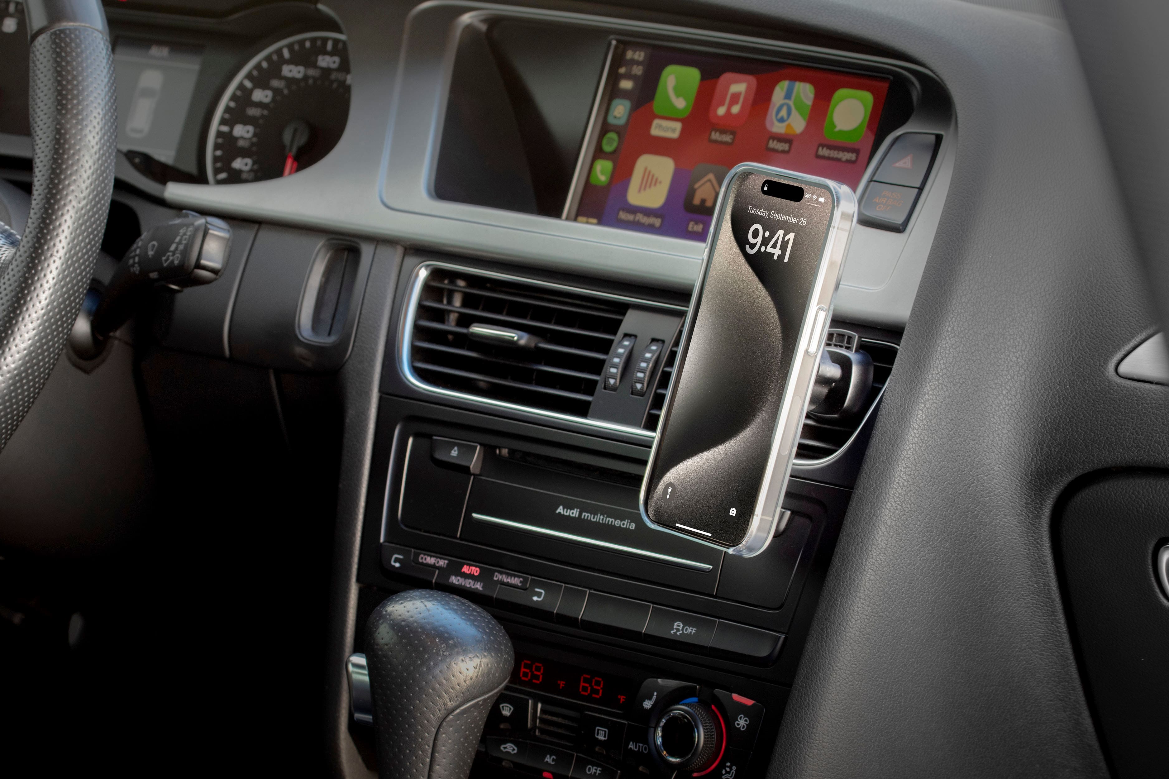 The image shows a car's dashboard with a cell phone attached to the dashboard. The phone is displaying the time as 9:41. The car has a steering wheel and a clock on the dashboard. The car is equipped with an Audi multimedia system, which includes features such as phone, music, maps, and messages. The car's interior is designed with comfort and functionality in mind, offering a pleasant driving experience.