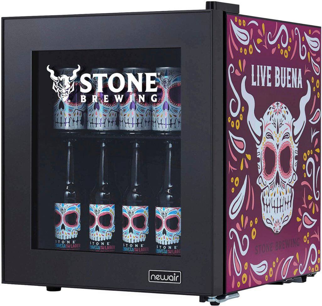 Stone Brewing Live Bueno Tone Lager is displayed in a black cooler with a skeleton on the front. The cooler is filled with cans of the lager, showcasing the beer in a visually appealing way. The skeleton adds a unique and eye-catching element to the presentation, making it stand out from other beer coolers.