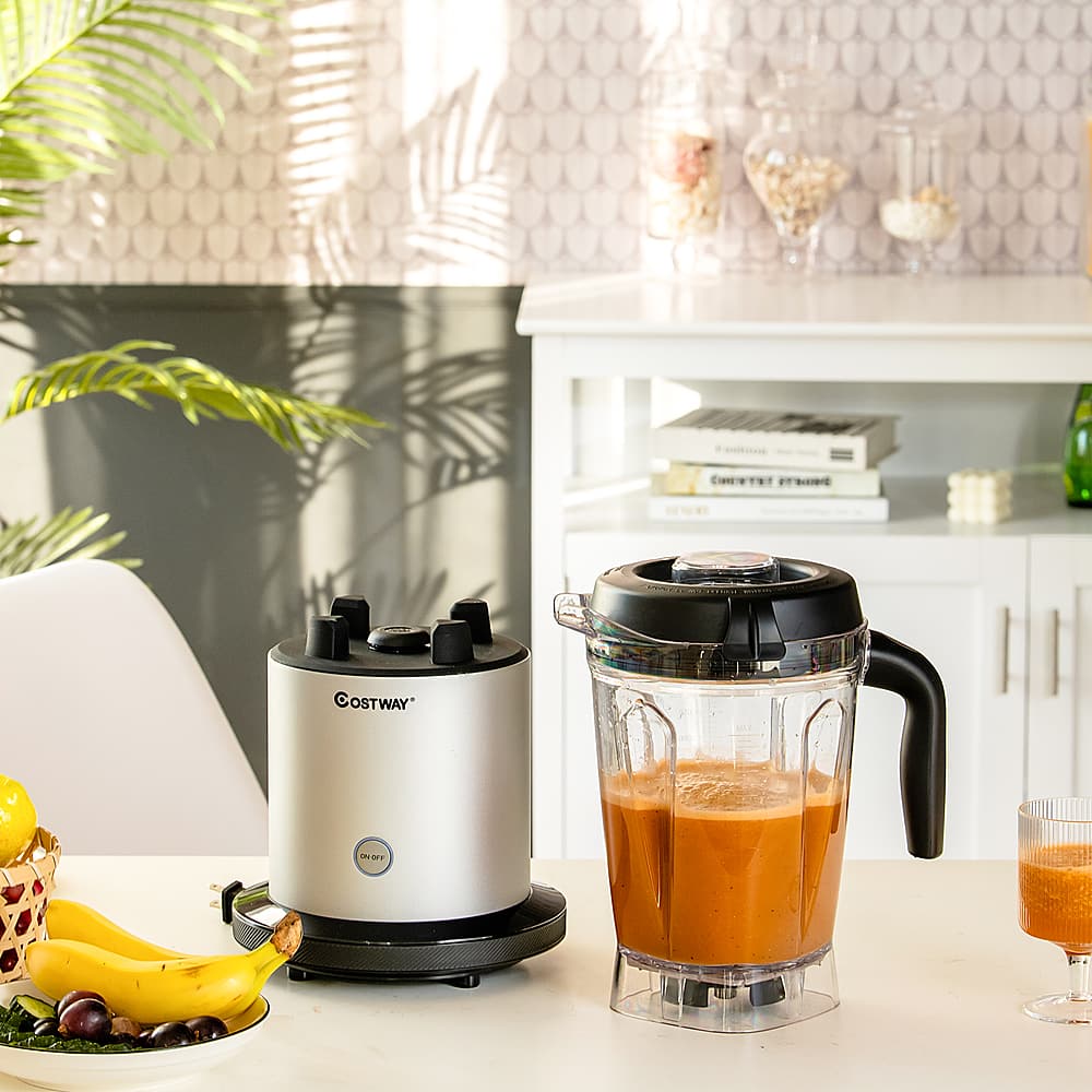 The text on the image reads "OSTWAY TOOT." However, it is not clear what the intended text is. The image shows a kitchen counter with a blender, a juicer, a bowl of fruit, and a banana. There are also books on the counter and a potted plant nearby.