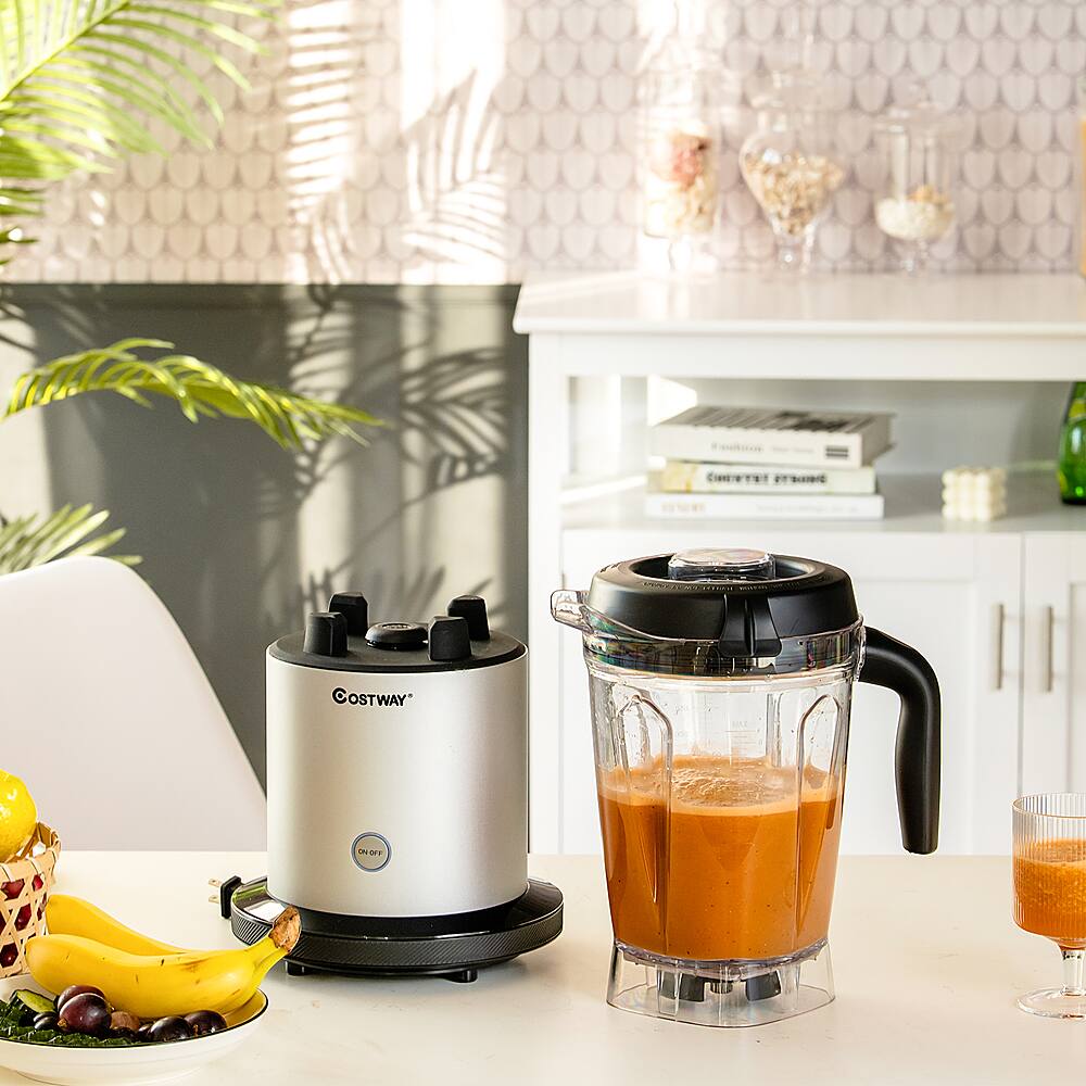 The text on the image reads "OSTWAY TOOT." However, it is not clear what the intended text is. The image shows a kitchen counter with a blender, a juicer, a bowl of fruit, and a banana. There are also books on the counter and a potted plant nearby.