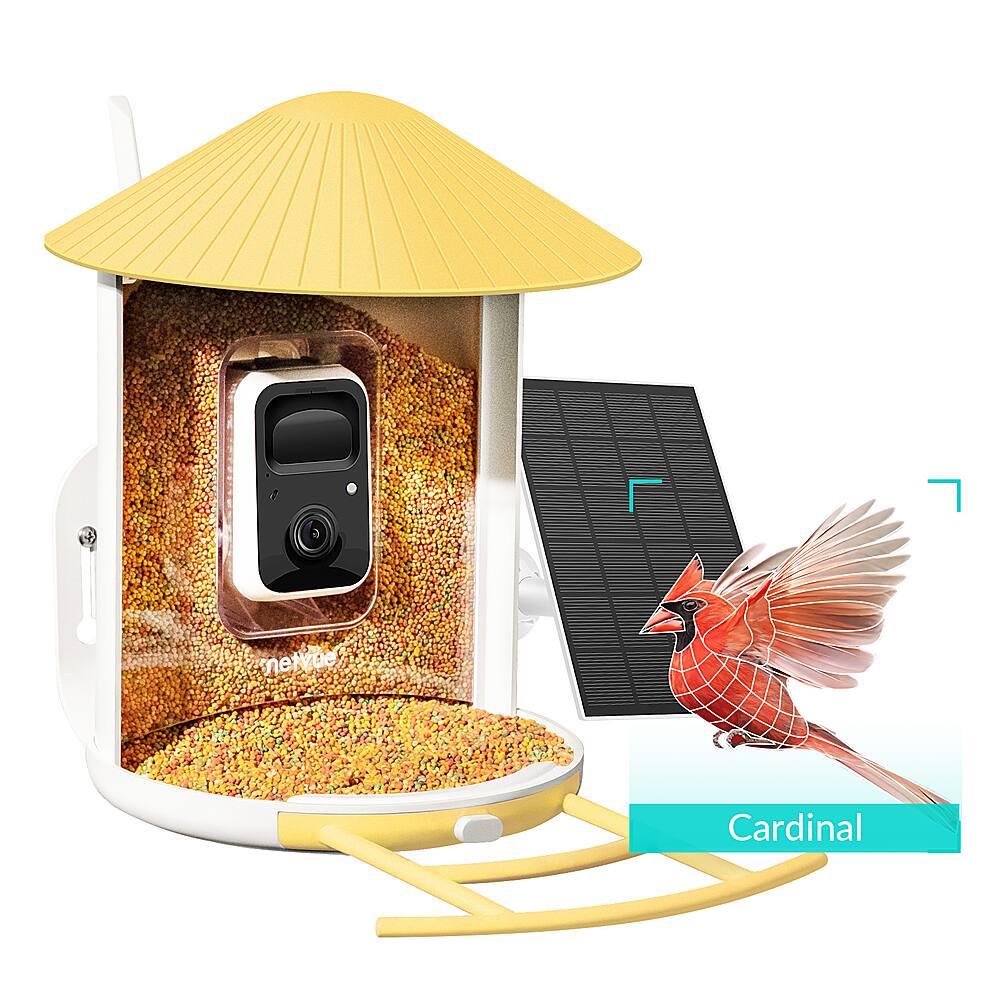 The image features a bird feeder with a solar panel on top, which is designed to attract birds. The feeder is filled with birdseed, and a bird is perched on the feeder, enjoying the food. The bird feeder is placed outdoors, and it is surrounded by a yellow umbrella, which adds a unique touch to the scene. The feeder is also equipped with a camera, allowing people to observe the bird's activities from a distance.