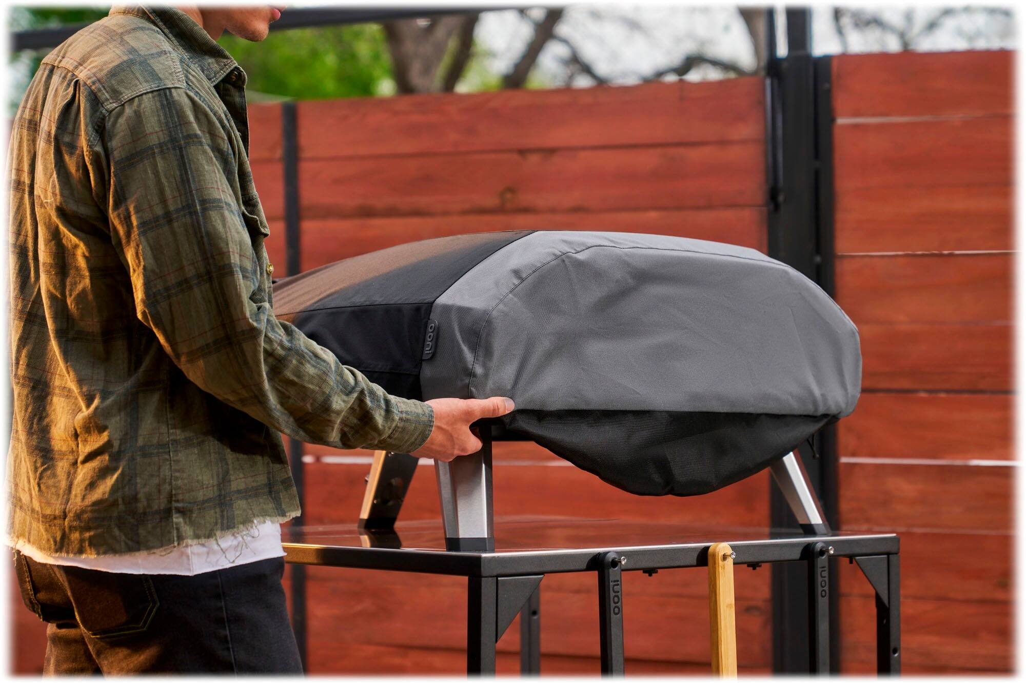 The man is holding a piece of luggage or a bag, which is placed on a table.
