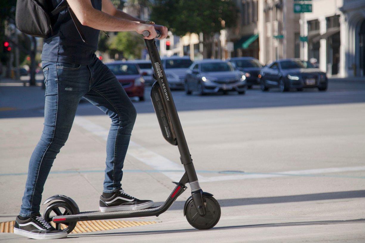 Zoom in on The man is riding a Segway scooter on the street.