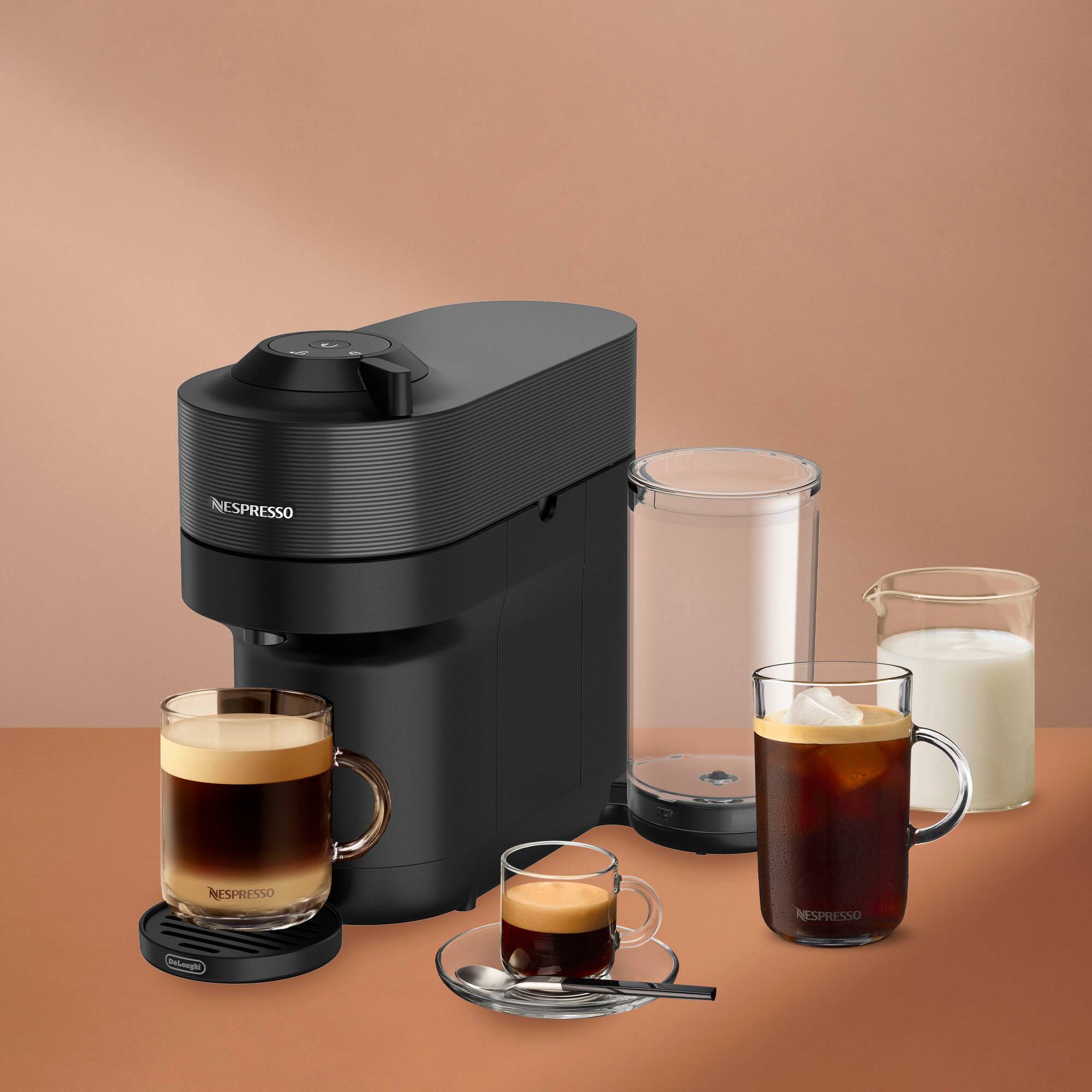 The image features a coffee maker, specifically a Nespresso machine, with a cup of coffee and a glass of milk on the table. There are also two cups of coffee and a glass of milk on the table. The machine is placed on a counter, and the cups are arranged around it.
