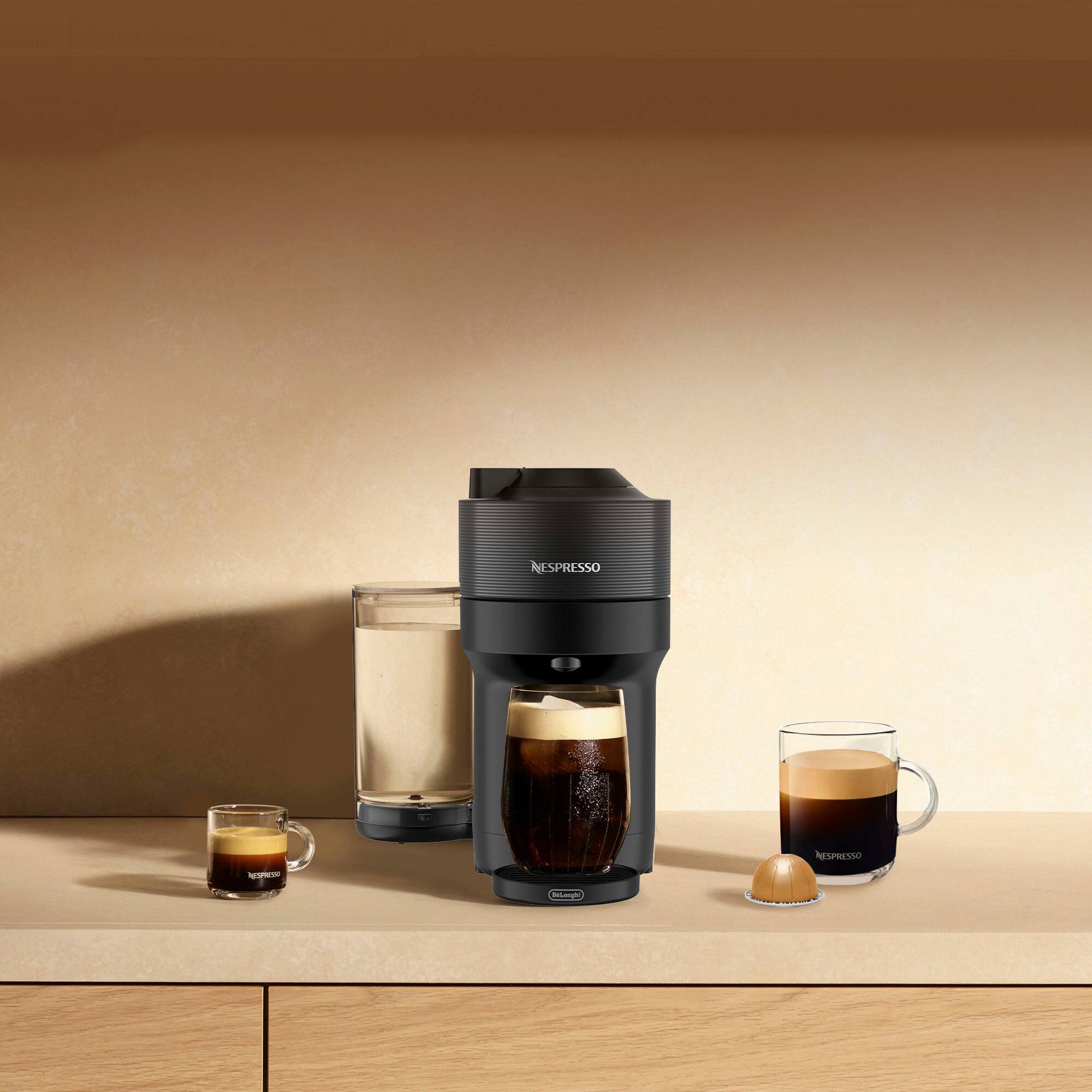 The image shows a Nespresso machine on a counter, with a glass of espresso and a glass of milk nearby. There are also two cups of coffee, one of which is a cappuccino. The machine is surrounded by various drinks, including a glass of milk and a glass of espresso. The scene suggests that someone is enjoying a variety of beverages from the Nespresso machine.
