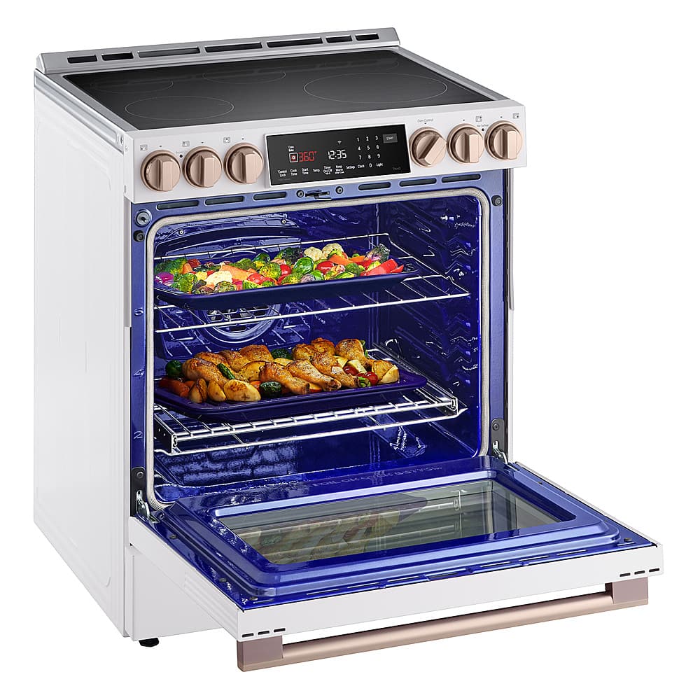 The image shows a white oven with a blue interior. The oven is filled with various foods, including a tray of chicken and a tray of vegetables. The oven has a digital display, which shows the time and temperature. The oven is open, revealing the food inside.