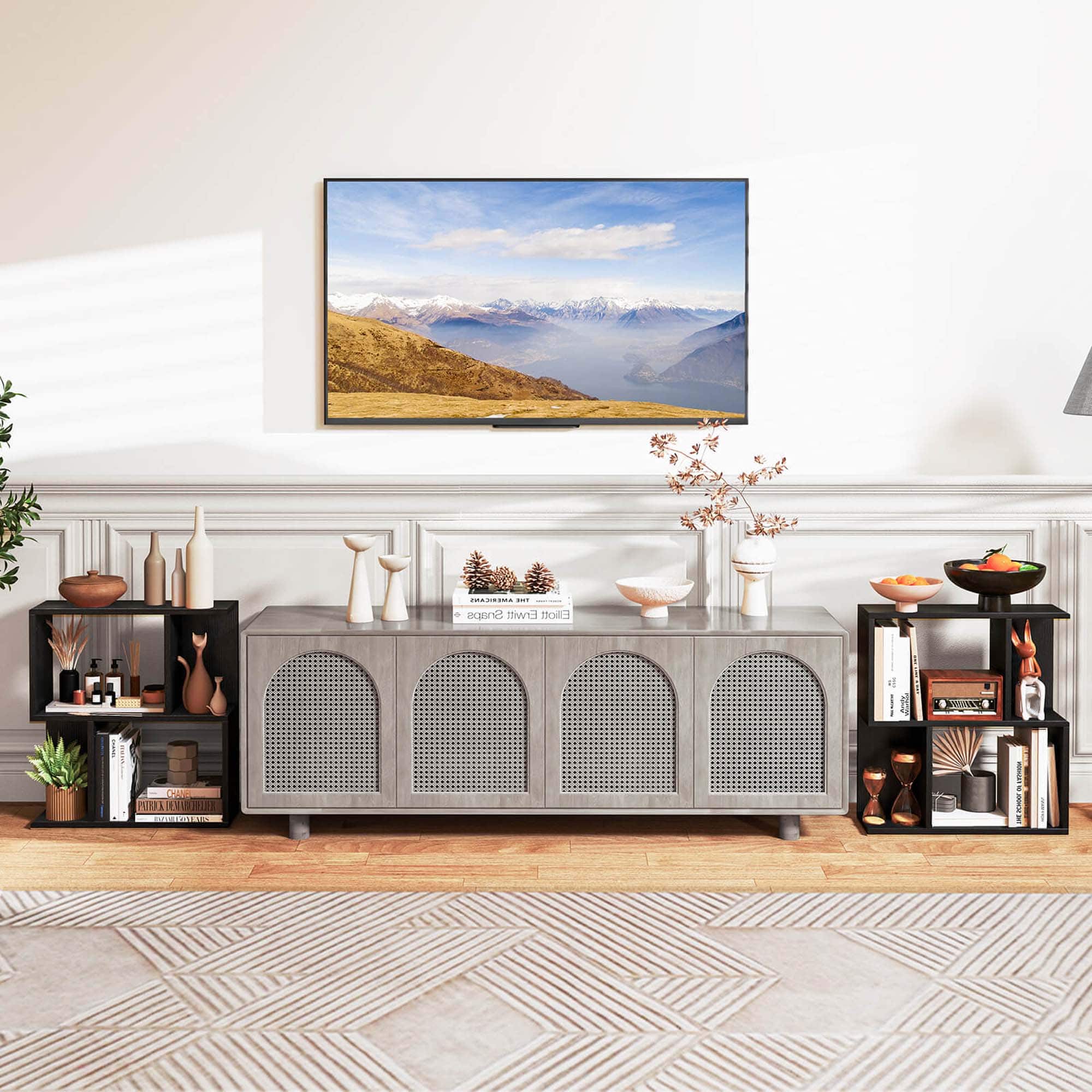 The image shows a living room with a flat screen TV mounted on the wall. The room is decorated with various items such as a potted plant, a vase, a bowl, a book, and a clock. There is also a table with a bowl on it. The room appears to be well-organized and comfortable, with a cozy atmosphere.