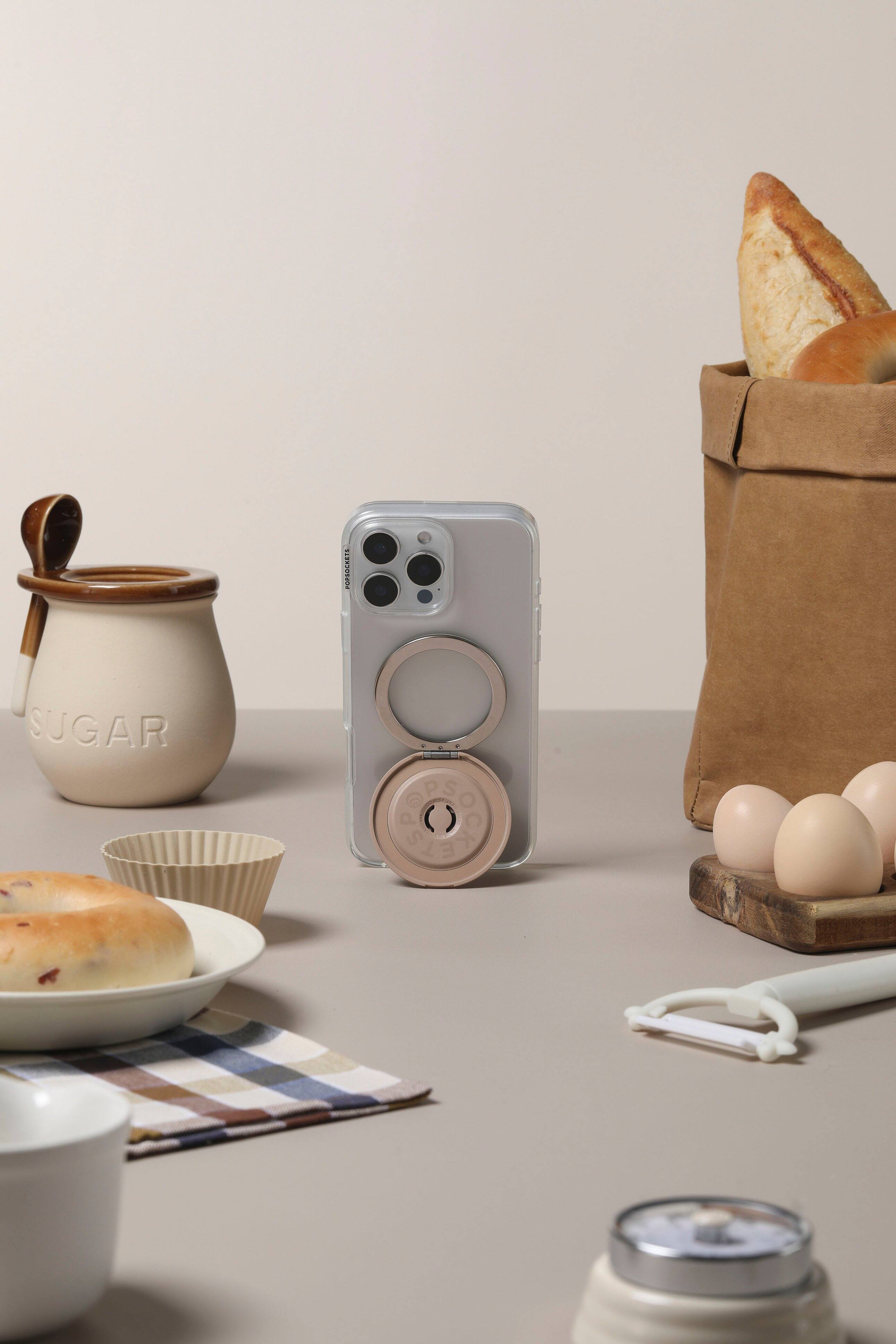 The image shows a table with various items on it, including a toaster, a bag of bread, and a bowl of food. There is also a cup and a spoon present on the table. The table appears to be set for a meal, with the food and utensils arranged neatly.