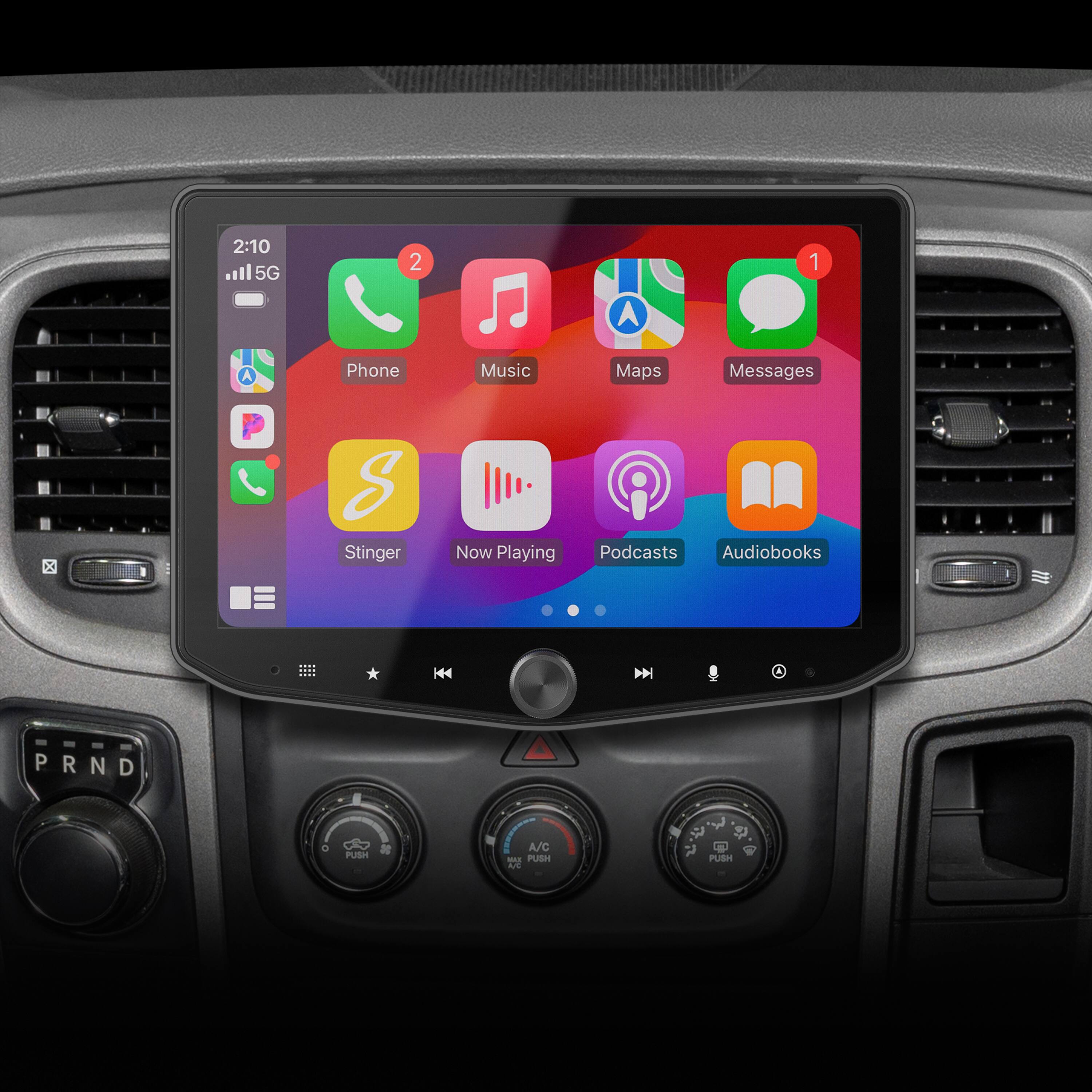 The image shows a car's dashboard with a built-in display screen. The screen displays various apps, including a phone, music, maps, messages, and podcasts. The car also has a radio and audiobooks available as options. The car's dashboard also has buttons for controlling the air conditioning and other functions. The time displayed on the screen is 2:10.