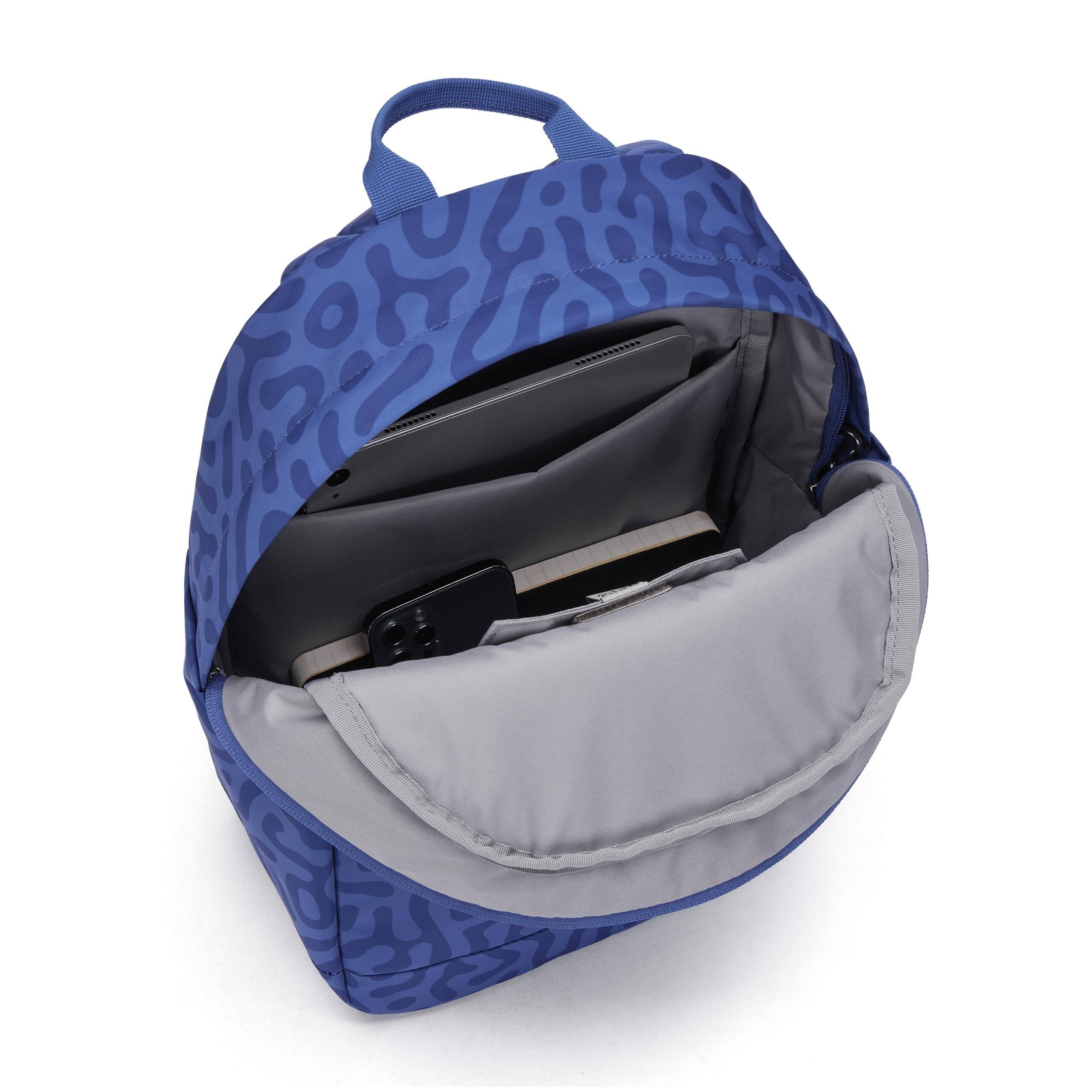 The image shows a blue and gray backpack with a patterned design. Inside the backpack, there is a black laptop and a smartphone.