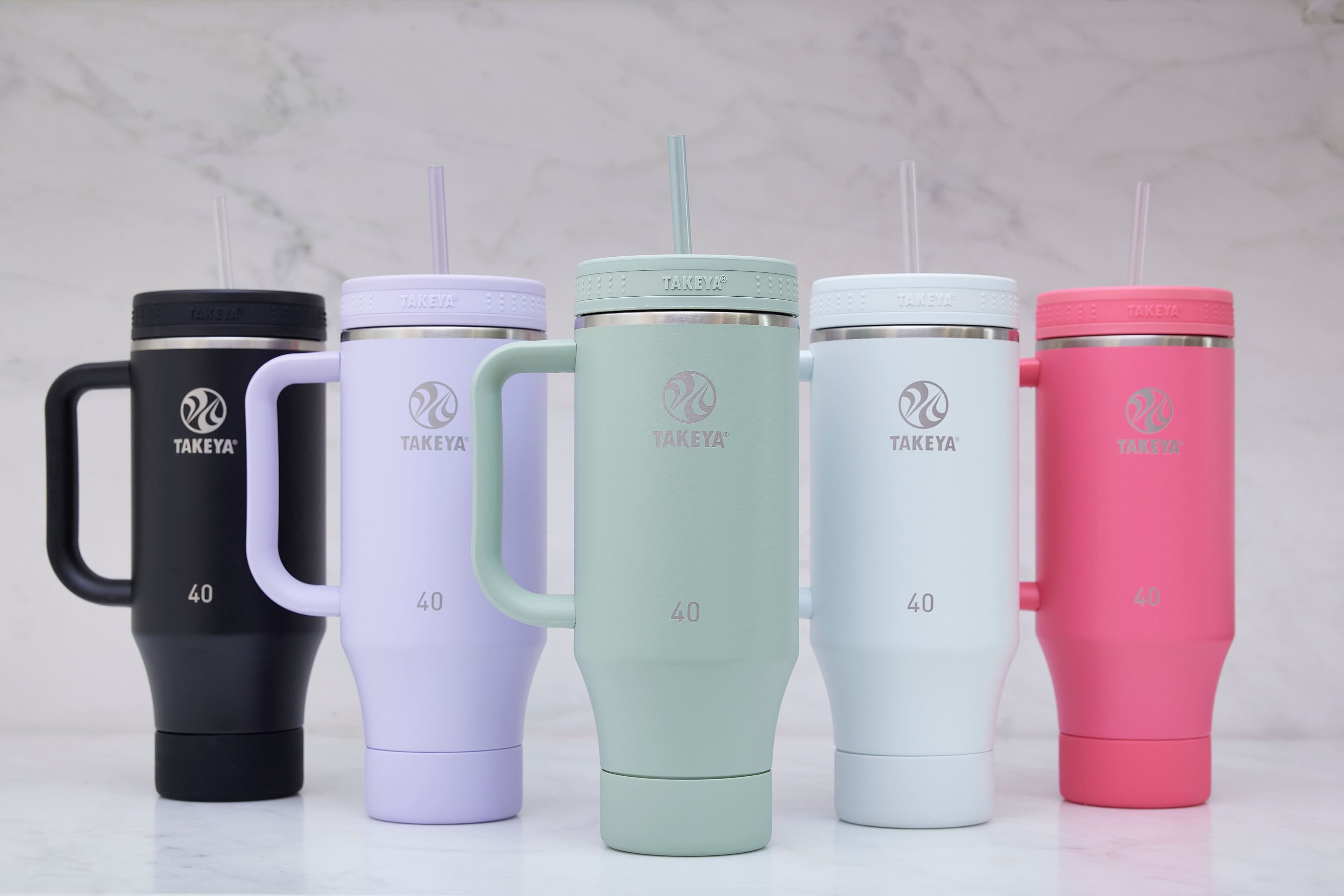 The text on the image reads: "TAKEYA BE SE TAKEYA BEEBEE SE9BE TAKEVA BR 12 TAKEYA E BBEE TAKEYA BER 2 TAKEYA TAKEYA TAKEYA TAKEYA TAKEYA D 40 I 40 40 40 40."
Corrected text: "TAKEYA BE SE TAKEYA BEEBEE SE9BE TAKEVA BR 12 TAKEYA E BBEE TAKEYA BER 2 TAKEYA TAKEYA TAKEYA TAKEYA TAKEYA D 40 I 40 40 40 40."
The text is describing the different colors of the Takeya branded coffee mugs, which are available in 40 oz sizes.