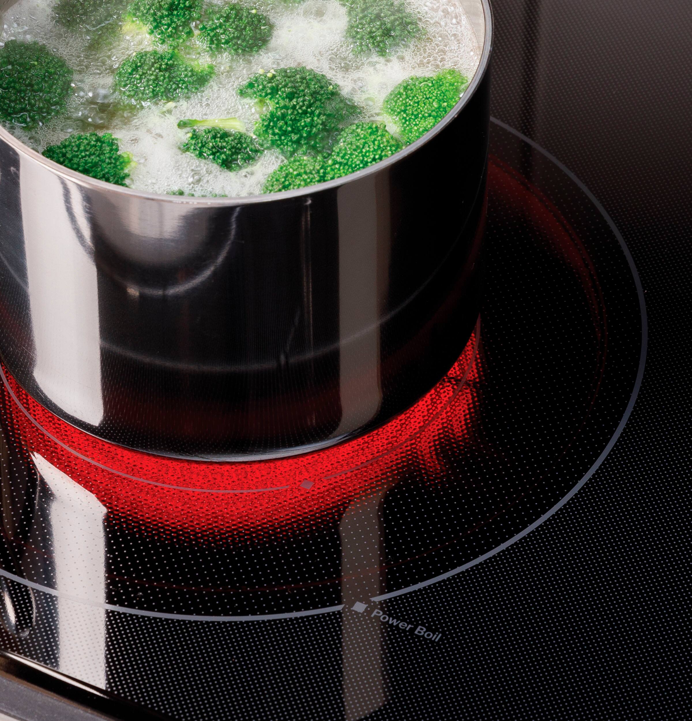 The image shows a pot of broccoli on a stove, with the stove's heat turned on. The broccoli is placed on a red heating element, and the pot is filled with water. The stove's heat is turned on to cook the broccoli, which is a healthy and nutritious vegetable.