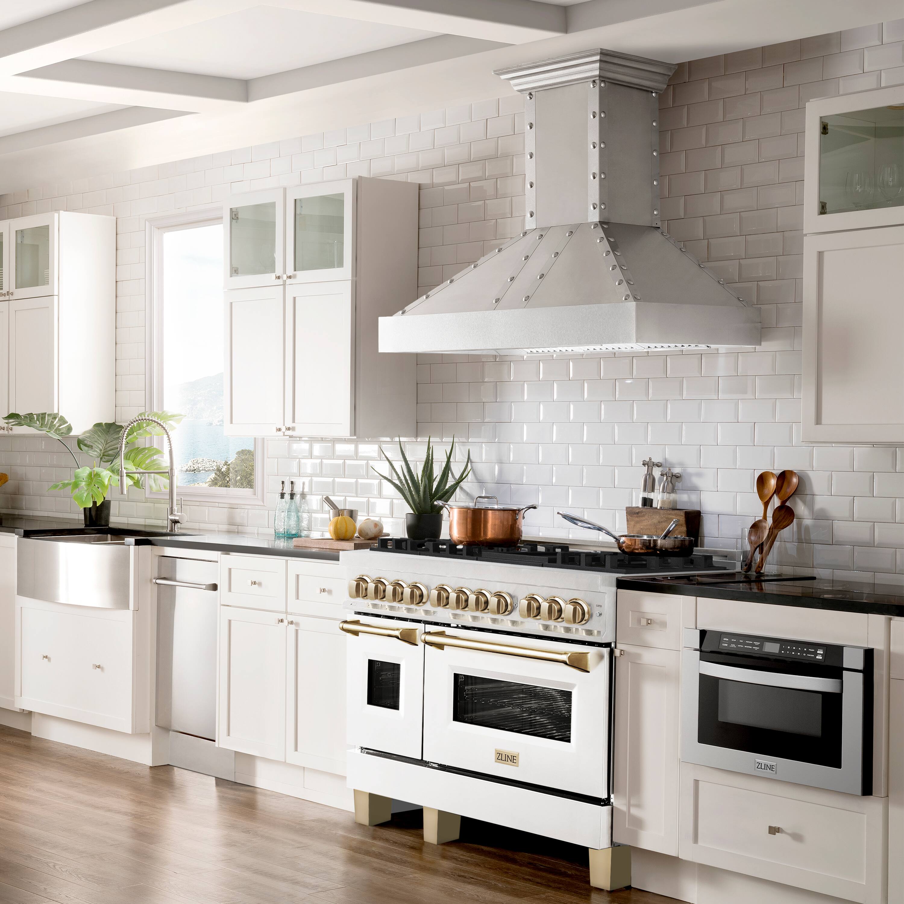 The image features a large, white kitchen with a stove top oven, a sink, and a window. The kitchen is equipped with a variety of utensils, including knives, spoons, and bowls. There are also several bottles and a potted plant in the kitchen. The oven is positioned under a ventilation hood, which is designed to remove heat and smoke from the cooking area. The kitchen is well-lit, with natural light coming through the window, and it appears to be a modern, well-equipped space.
