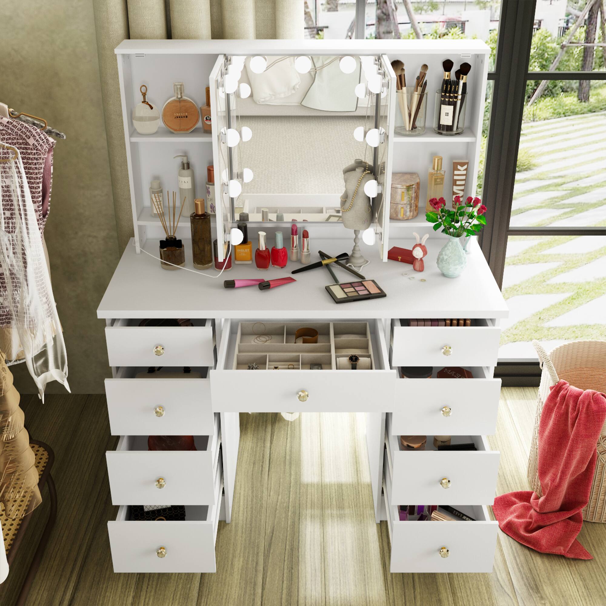 The image shows a white vanity table with a mirror surrounded by lights. The table has multiple drawers and shelves, with various beauty products and makeup items neatly arranged on it. There are brushes, bottles, and a small vase with flowers on the surface. The vanity is situated in a well-lit room with a window in the background.