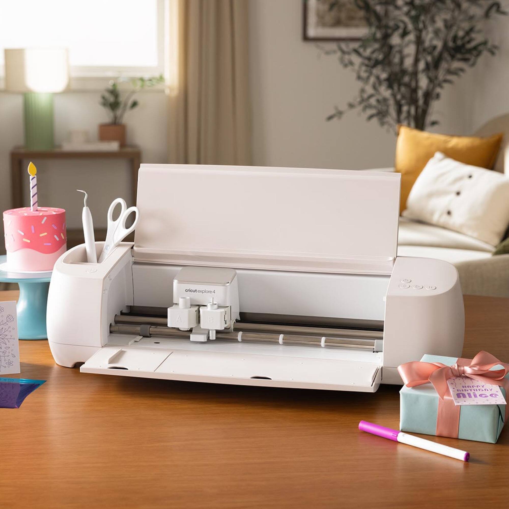 The image displays a white printer sitting on a wooden table. Next to the printer, there is a cake with a candle on it, and a pair of scissors. The table also has a cup and a bowl on it. The scene appears to be a celebration or a special occasion, with the printer possibly being used for printing decorations or invitations.