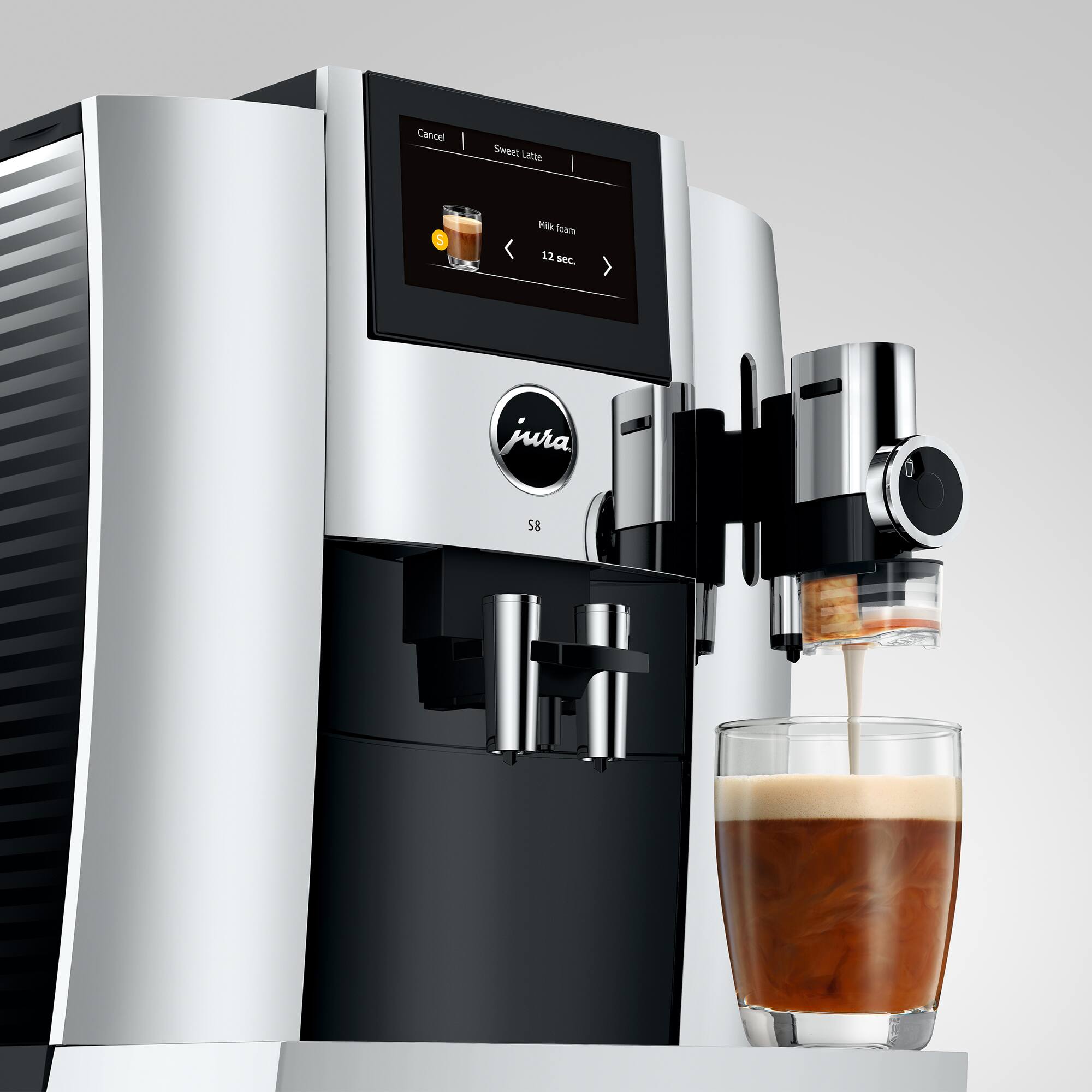 The image shows a coffee machine with a cup of coffee being poured from it. The machine is a Jura 58, and the coffee is being poured into a glass. The coffee machine is equipped with a digital display, which shows the time and temperature of the coffee being brewed. The coffee is being poured at a temperature of 12 seconds, and the machine is canceling the sweet latte.
