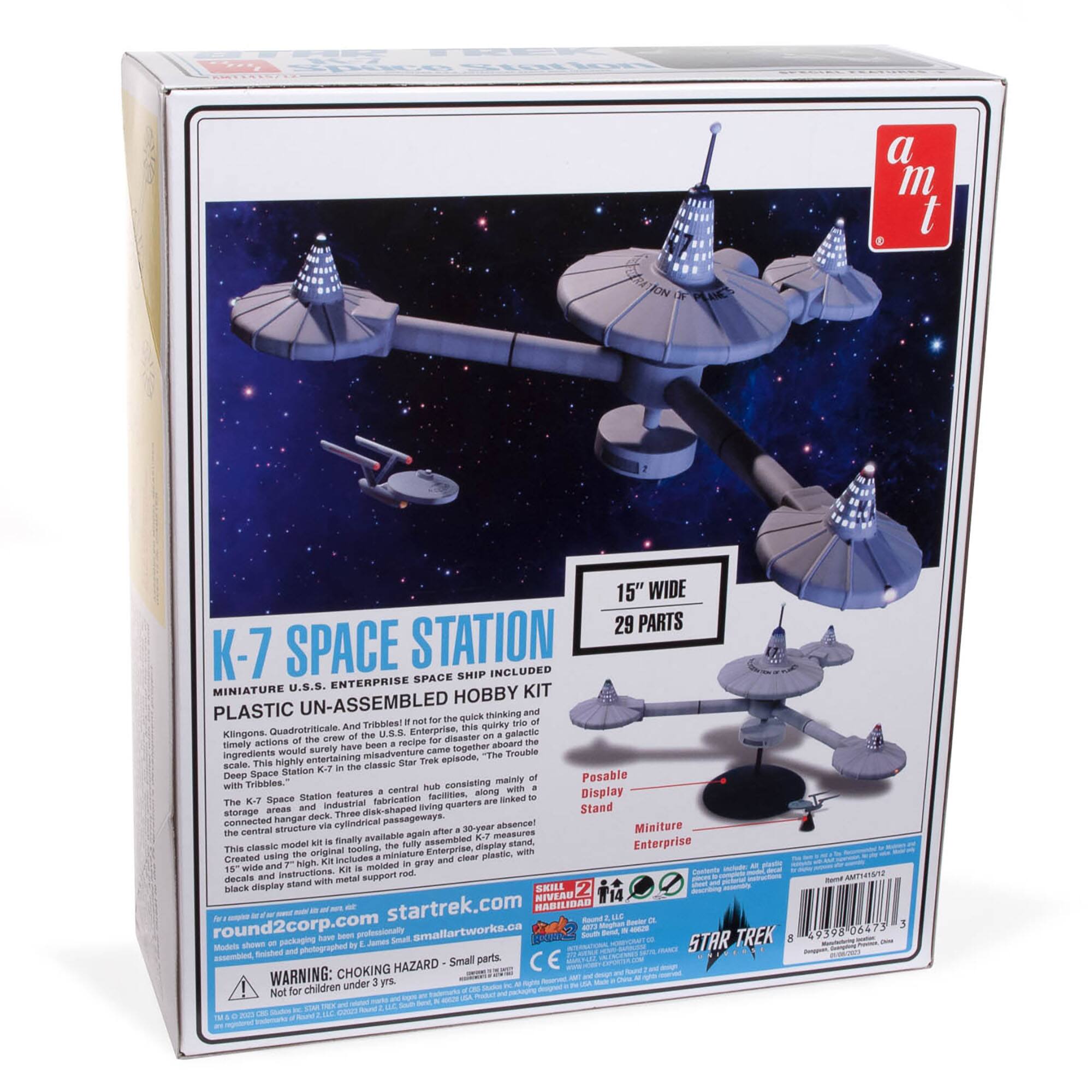 The image features a box of a K-7 Space Station model kit, which includes a U.S.S. Enterprise space miniature. The kit is made of plastic and has 29 parts. The box also includes a display stand and a storage area for the model. The kit is designed for assembly and is a classic Star Trek model. The box is labeled with the dimensions of the model and the materials used.