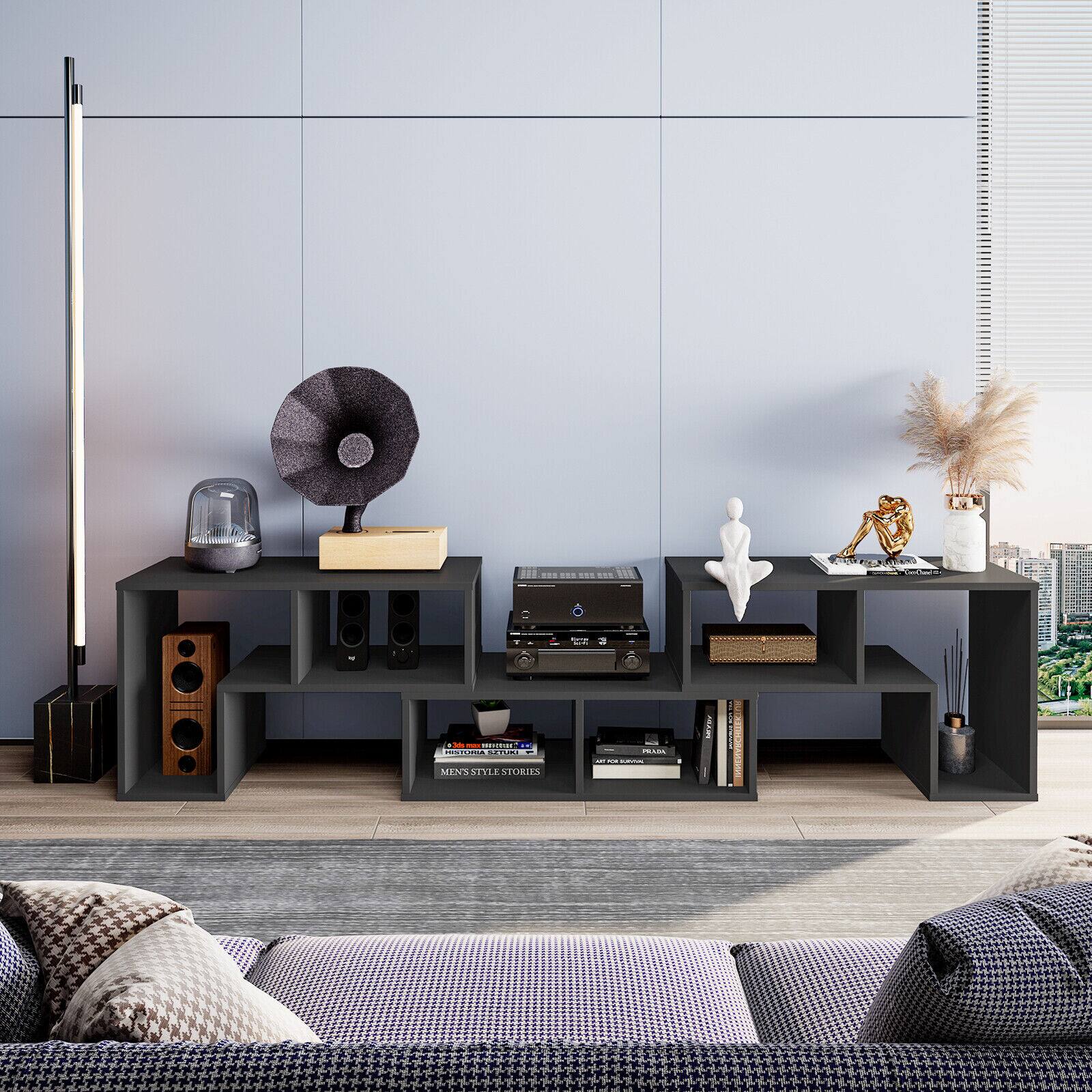 The image features a living room with a couch, a table, and a television. There are also several books and a vase in the room. The television is positioned on a stand, and the couch is located in the corner of the room. The overall atmosphere of the living room appears to be comfortable and inviting.