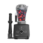 The image shows a Vitamix blender with a container full of berries, including blueberries and raspberries. The blender is black and silver, and it is placed on a countertop. The container of berries is placed inside the blender, ready to be blended.