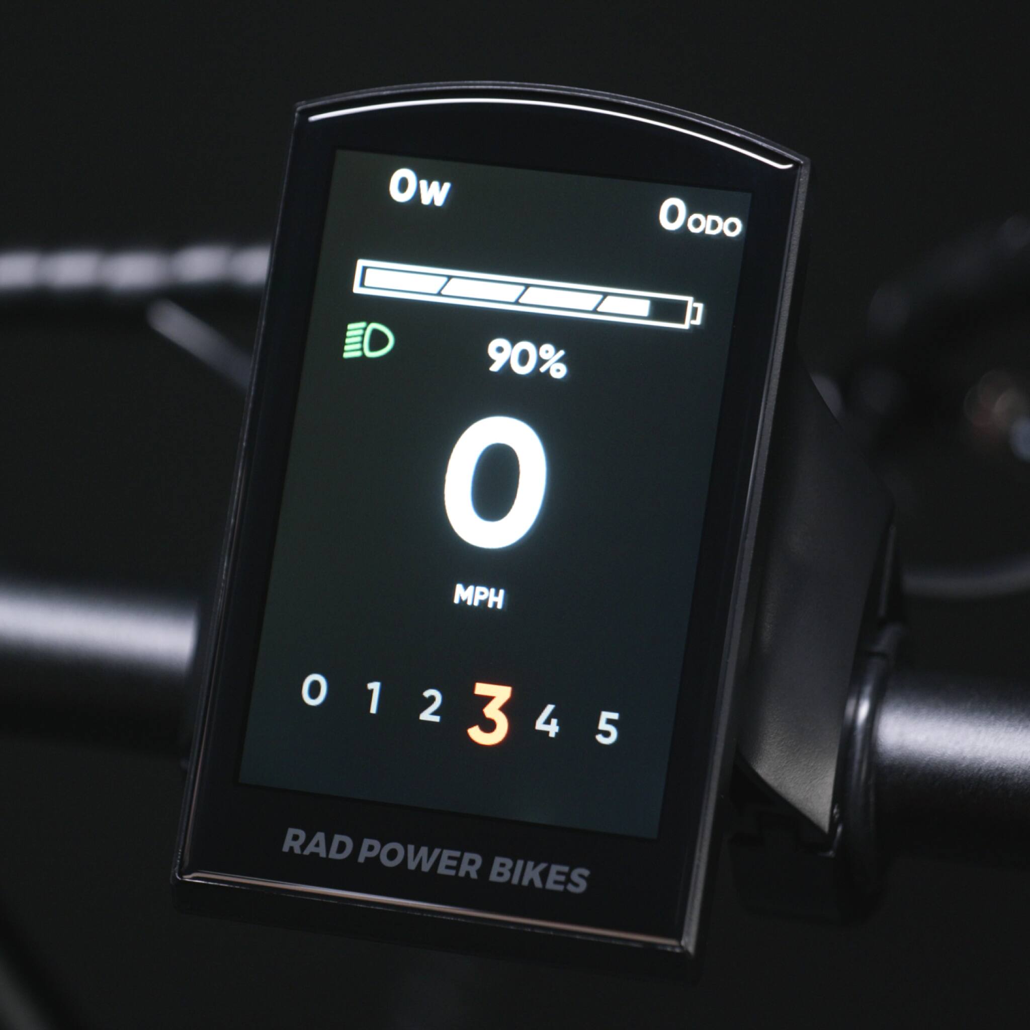 The text on the image reads: "Ow OODO D 90% O MPH J 012 O 1 2 3 4 5 RAD POWER BIKES." The correct grouping and text would be: "OW OODO D 90% O MPH J 012 O 1 2 3 4 5 RAD POWER BIKES."