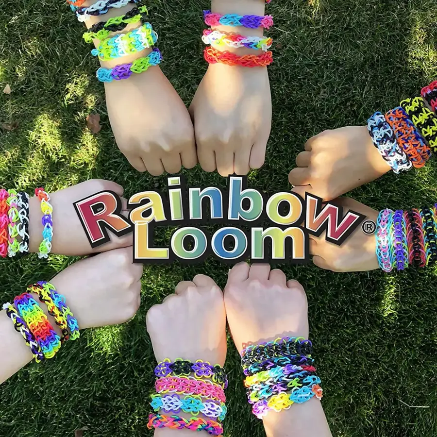 A group of people are holding hands and wearing colorful bracelets, forming a circle. They are promoting a product called Rainbow Loom.
