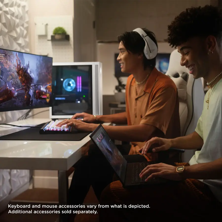 The image shows two men sitting at a table with laptops, keyboards, and mice. The text on the image states that the keyboard and mouse accessories may vary from what is depicted and that additional accessories are sold separately.