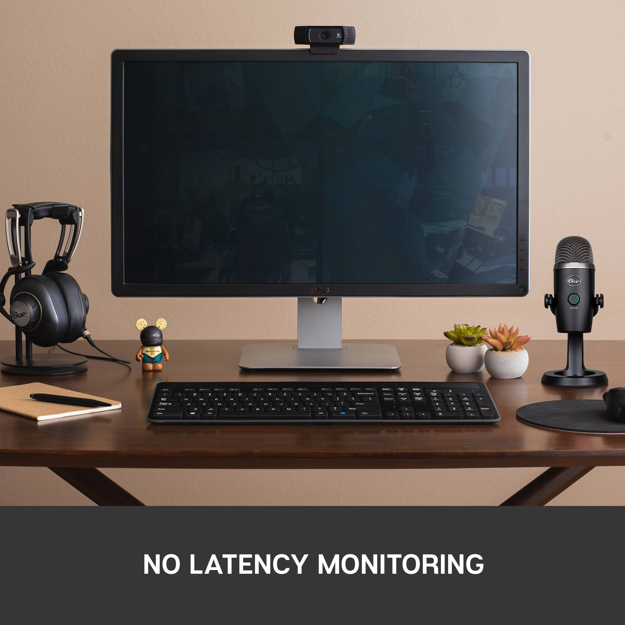 The image features a computer setup on a desk, including a monitor, keyboard, and mouse. There is also a microphone and a potted plant nearby. The text on the image reads "No latency monitoring," which suggests that the computer setup is optimized for low latency and fast response times. This is particularly important for tasks that require real-time processing, such as gaming or video editing.