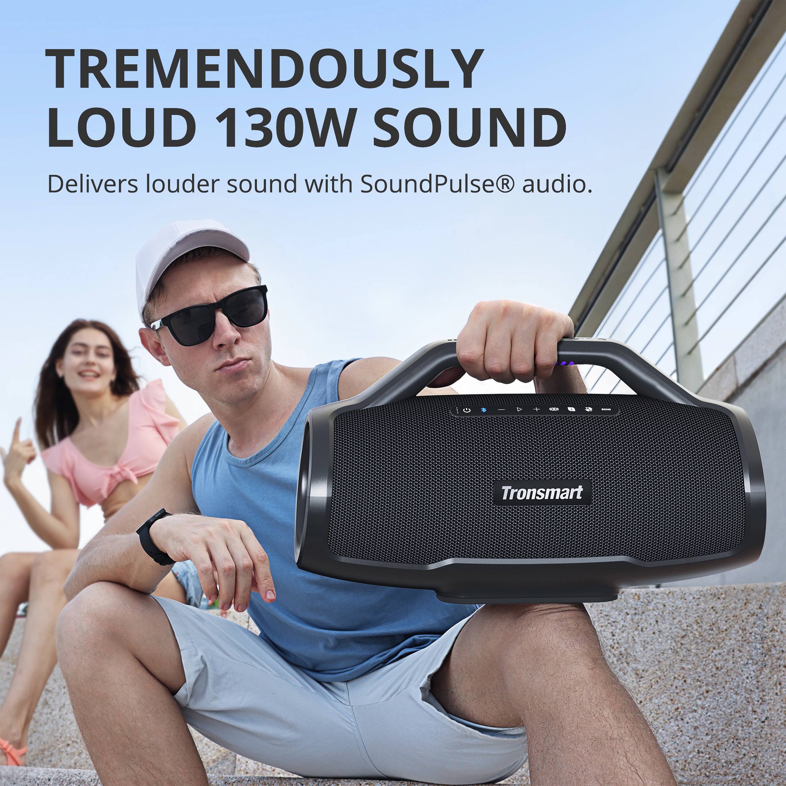The image features a man holding a black portable speaker, which is advertised as delivering "tremendously loud" sound with SoundPulse R audio. The man is sitting on a staircase, and there is a woman standing behind him. The advertisement emphasizes the speaker's ability to produce a high-quality audio experience, making it an attractive option for those seeking a powerful and effective speaker for their needs.