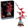 The image features a LEGO Plum Blossom tree, which is part of the LEGO Botanical Collection. The tree is made up of many small red flowers, and it is displayed in a box. The box contains 1550 pieces, and the tree is made up of 18+ pieces. The tree is a beautiful addition to any LEGO collection or display.