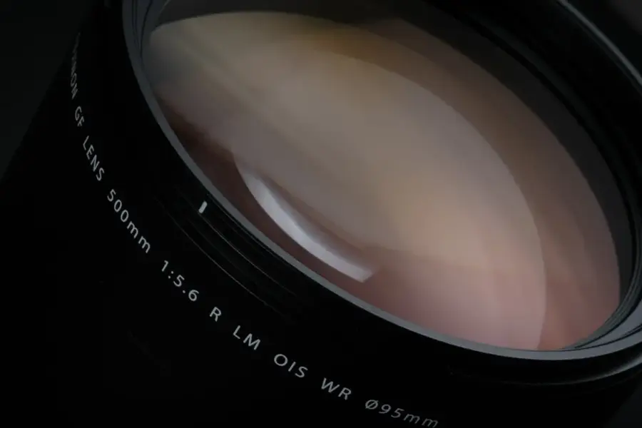The image features a large lens with a focal length of 500mm and an aperture of 1:5.6. The lens is designed for use with a Canon camera and has a maximum aperture of 0.95mm. The lens is also equipped with optical image stabilization (OIS) technology, which helps to reduce camera shake and improve image quality.