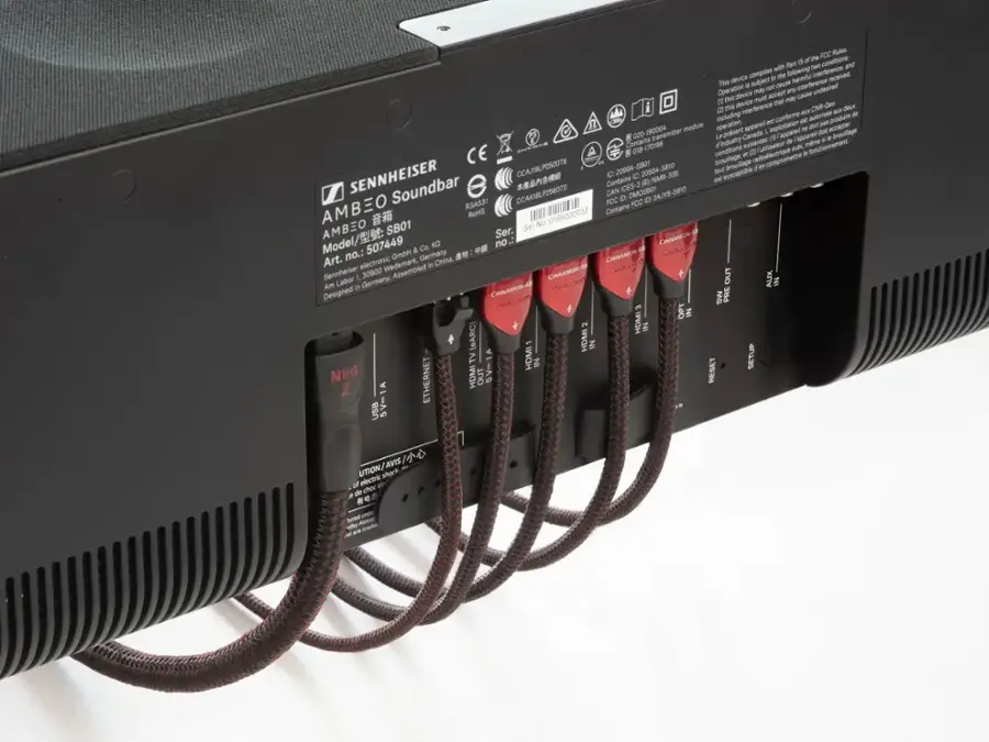 The text on the image is a combination of different languages, making it difficult to understand. However, based on the context, it seems to be related to a Sennheiser product, possibly an electronic device or a soundbar. The text also mentions a FCC, which could be a reference to the Federal Communications Commission. The presence of cords and connectors on the device suggests that it is designed for various input and output options.