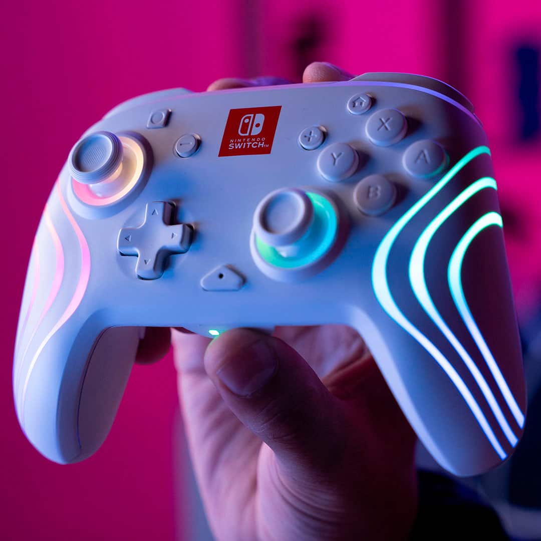 A Nintendo Switch controller is being held by a person. The controller has a brightly lit design and is being used to play a video game.