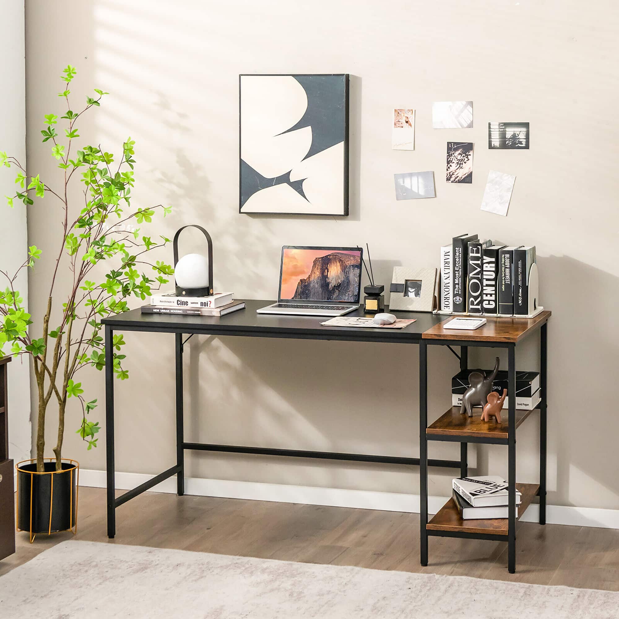 The image features a desk with a laptop and a lamp on it. There is also a bookshelf with a collection of books, including a book about Marilyn Monroe. The desk is situated next to a wall with a painting of a flower on it. Additionally, there is a potted plant in the room, adding a touch of greenery to the space.