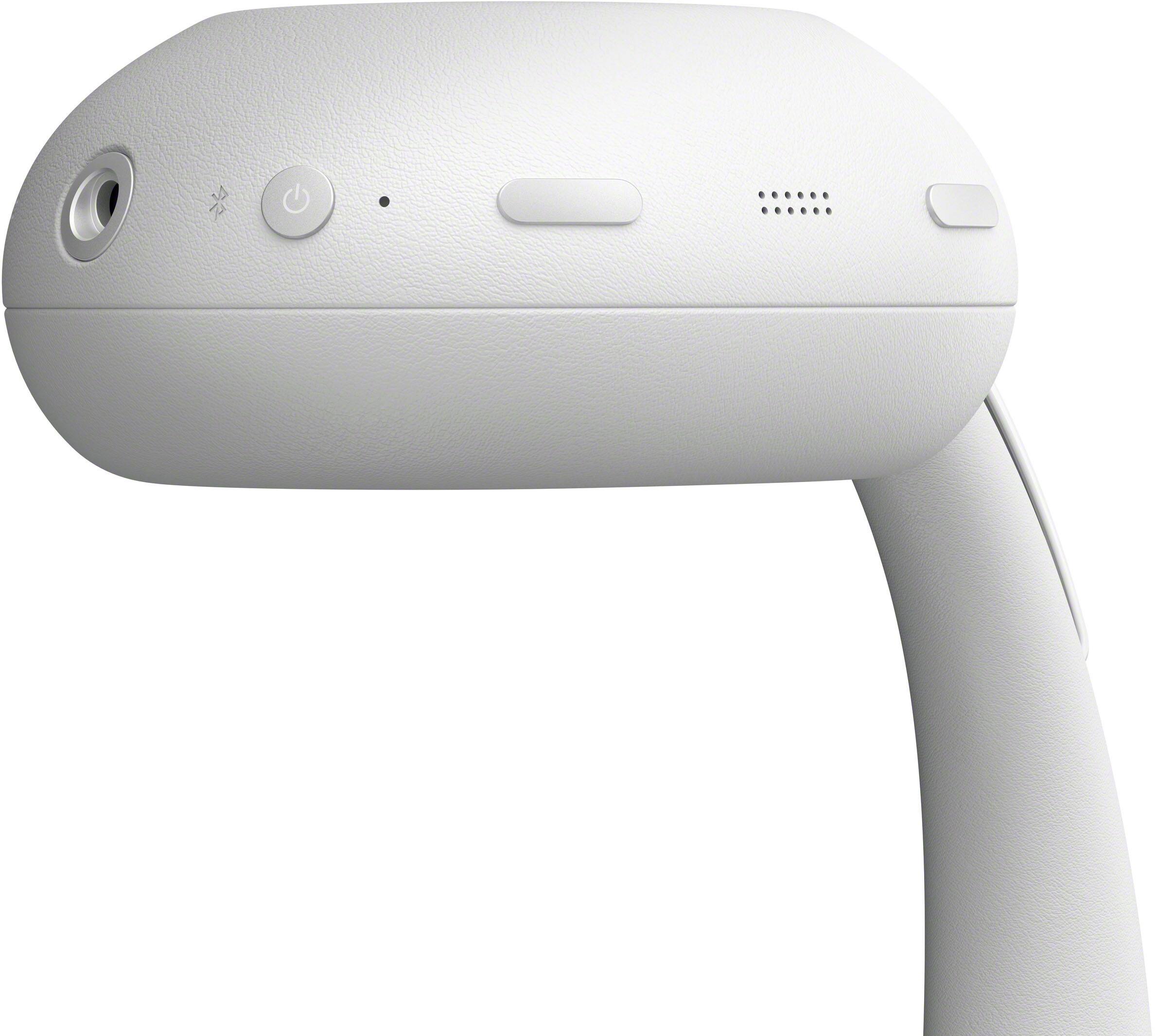 The image shows a close-up of a white, sleek, and modern-looking device with a curved design. On the front, there is a circular button, a power button, a small LED indicator, a rectangular button, and a small speaker grille.