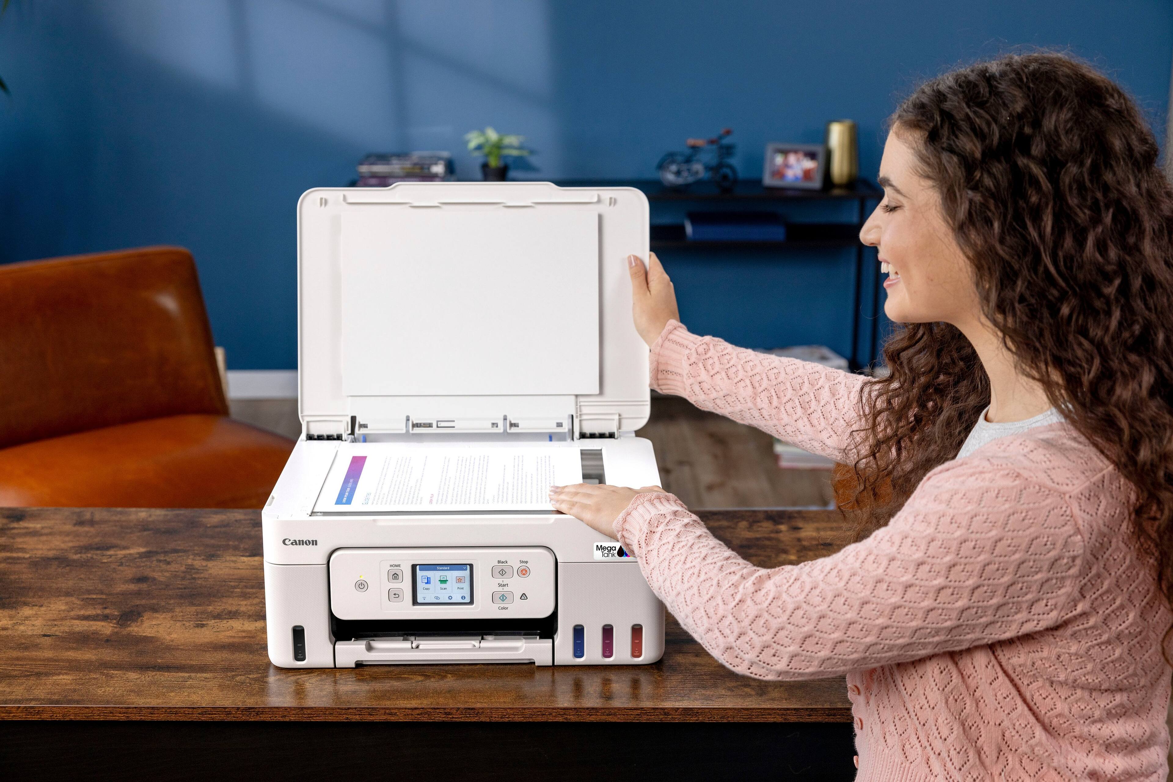 Canon printer is a great device for printing documents and photos. It is easy to use and offers a variety of features to enhance the printing experience. The woman in the image is demonstrating how to use the printer, showing that it is user-friendly and accessible to people of all ages and skill levels.