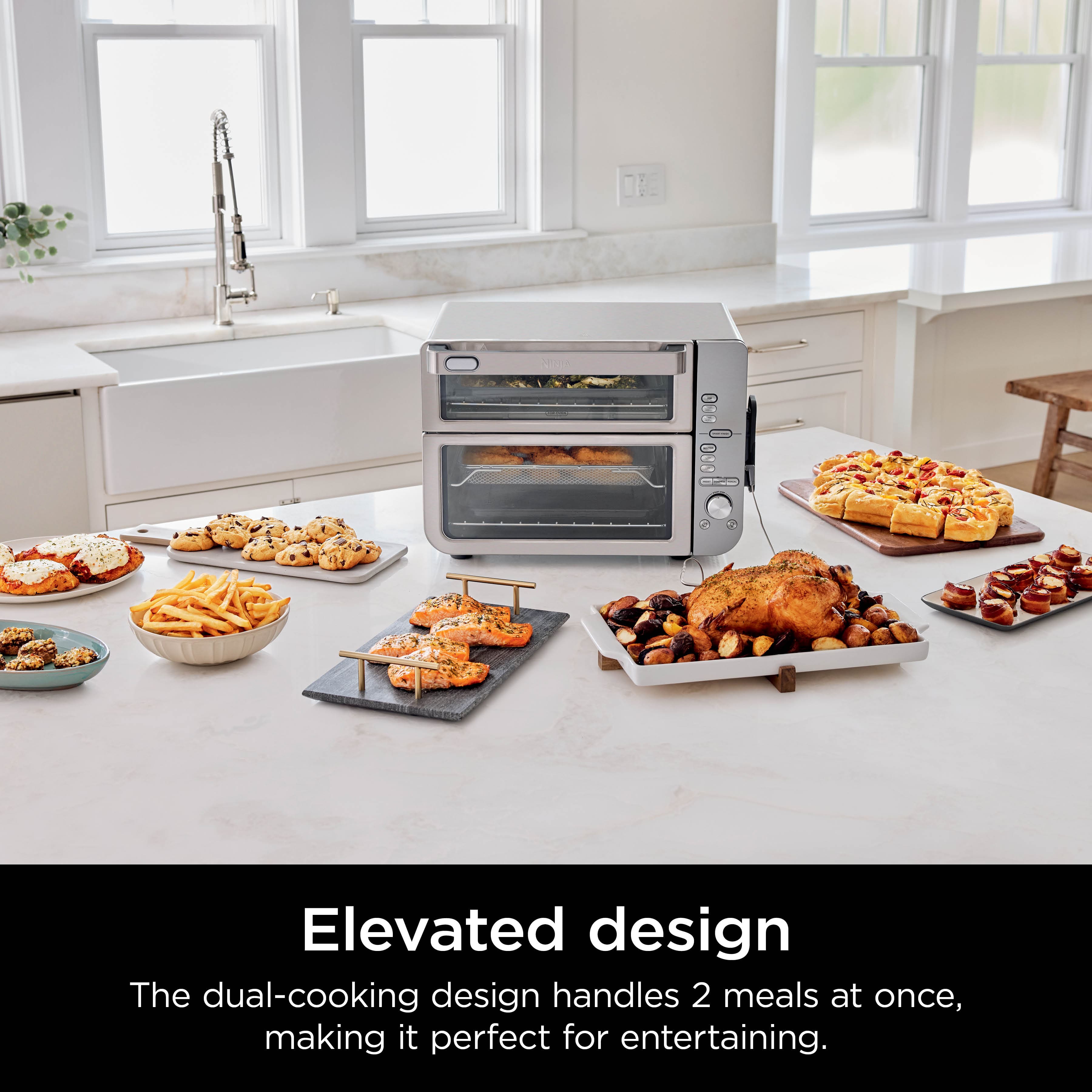The image features an elevated design that allows for the preparation of two meals at once, making it perfect for entertaining. The dual-cooking design is showcased with various food items, including a cake, pizza, and a bowl of fries, all placed on the counter. The microwave oven is placed on the counter, surrounded by the food items, and the sink is visible in the background. The image emphasizes the convenience and efficiency of this design for preparing meals and entertaining guests.