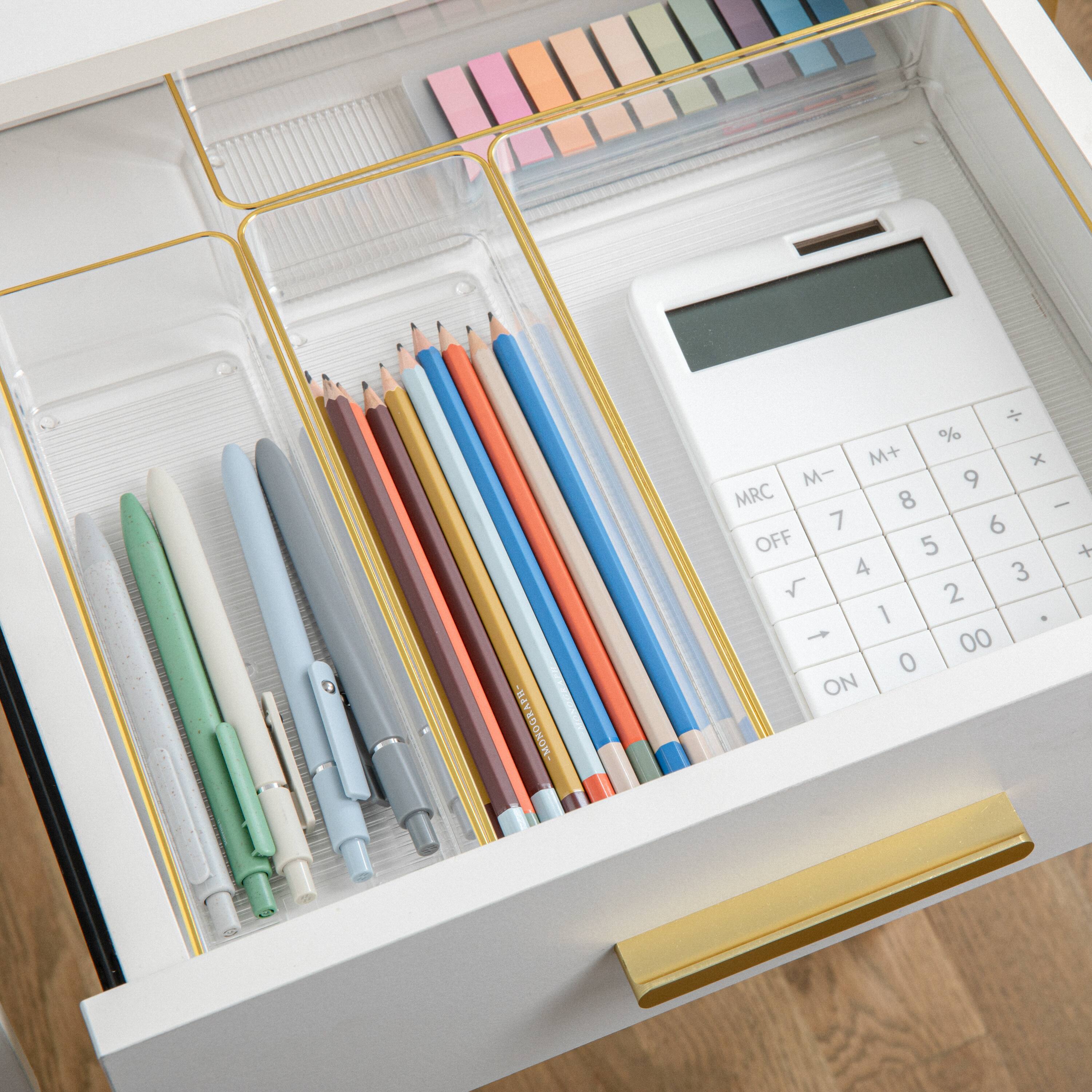 The text on the image reads: "AFW-MONOGRAPH M+ x M- 9 MRC 8 | 7 6 OFF 5 + 4 3 2 1 . t 00 0 ON". However, it is not clear what this text represents or how it relates to the image. The image features a desk with a drawer full of office supplies, including pens, pencils, and a calculator. The text does not seem to provide any context or information about the contents of the drawer.