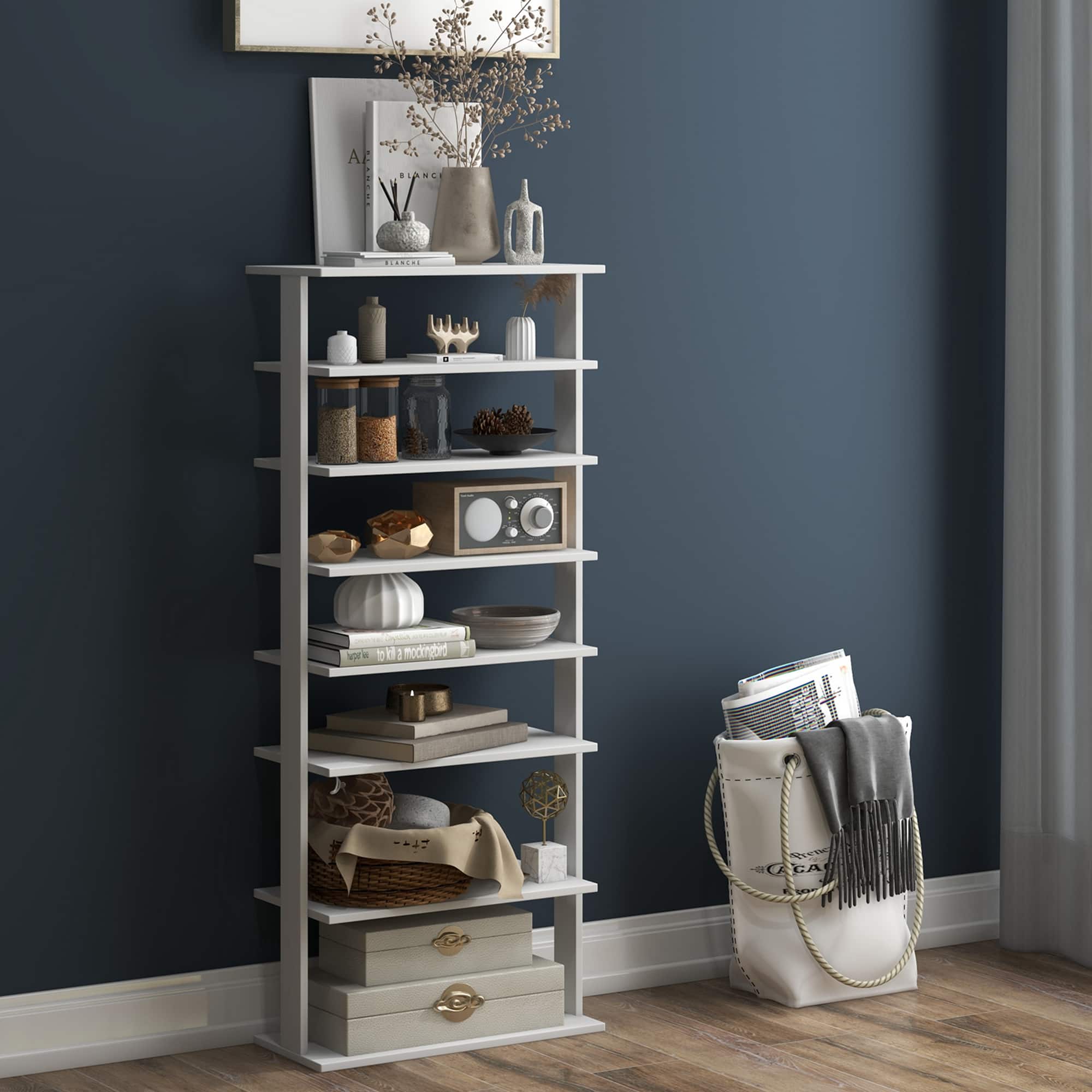 A white shelf with a variety of items on it, including books, a vase, and a potted plant. The shelf is placed against a blue wall.