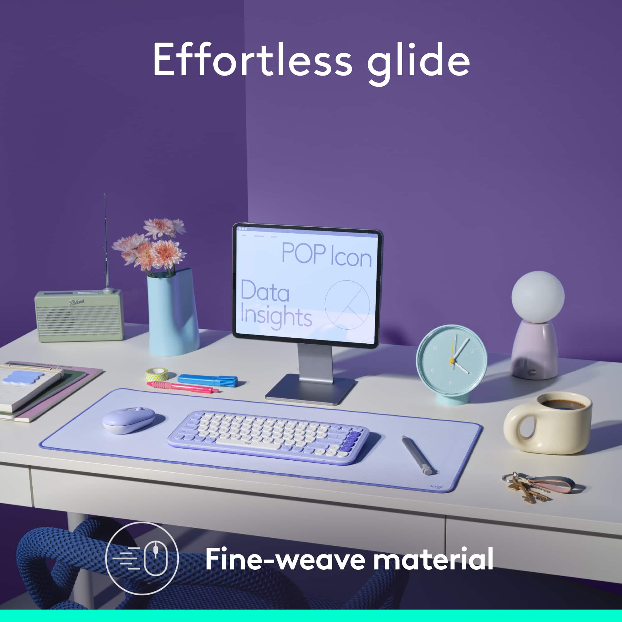 Effortless glide is a product that features a purple keyboard and mouse on a white desk. The desk also has a clock, a vase, a cup, and a book. The image is advertising the product and its features.