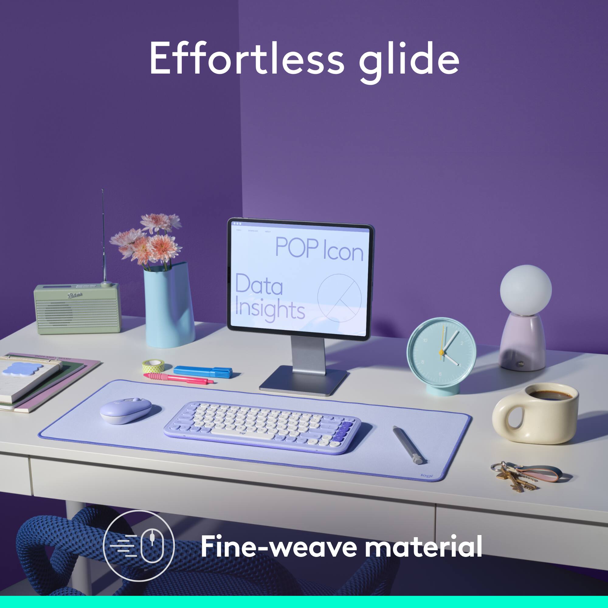 Effortless glide is a product that features a purple keyboard and mouse on a white desk. The desk also has a clock, a vase, a cup, and a book. The image is advertising the product and its features.